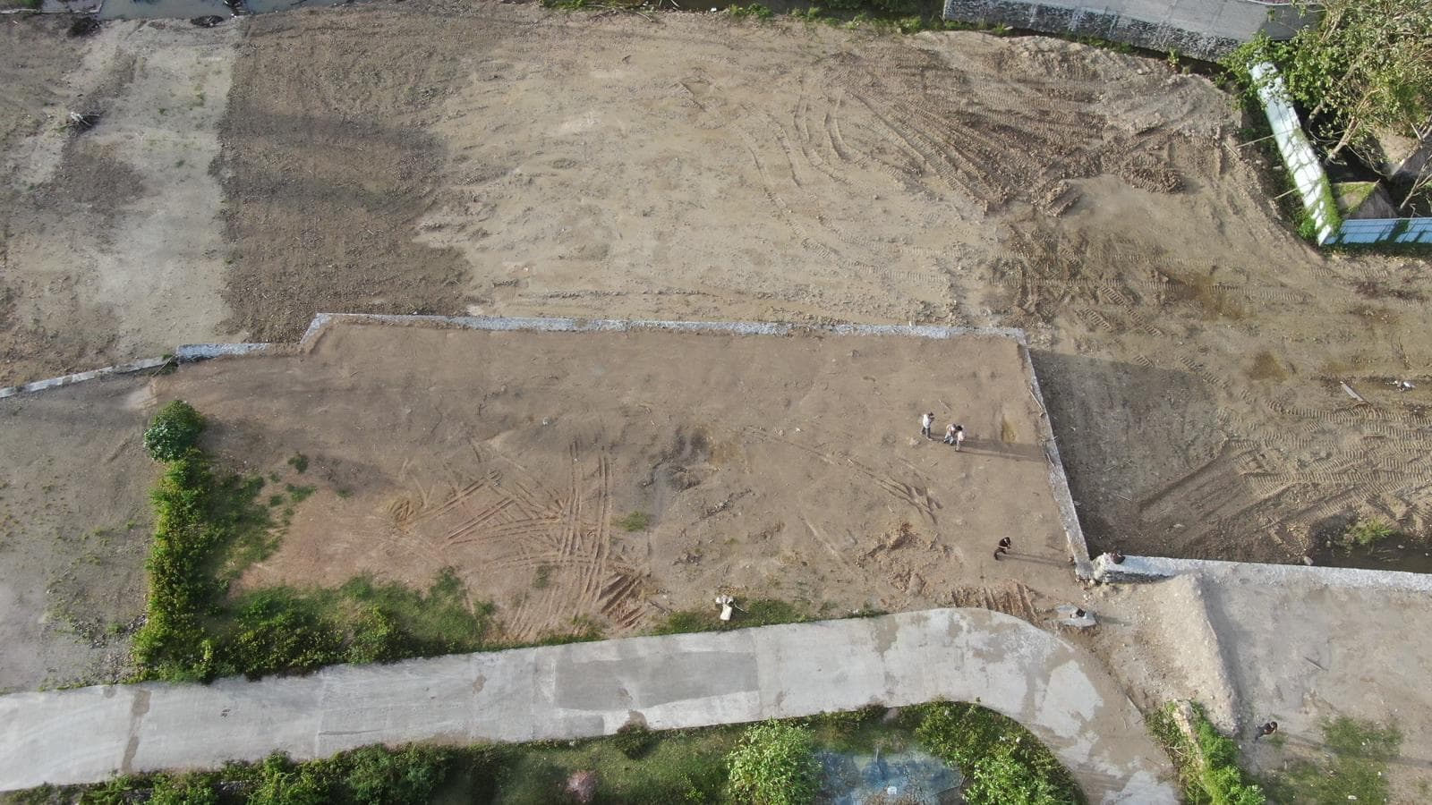 High-angle aerial view showing paved access roads surrounding leveled, cleared construction lots.