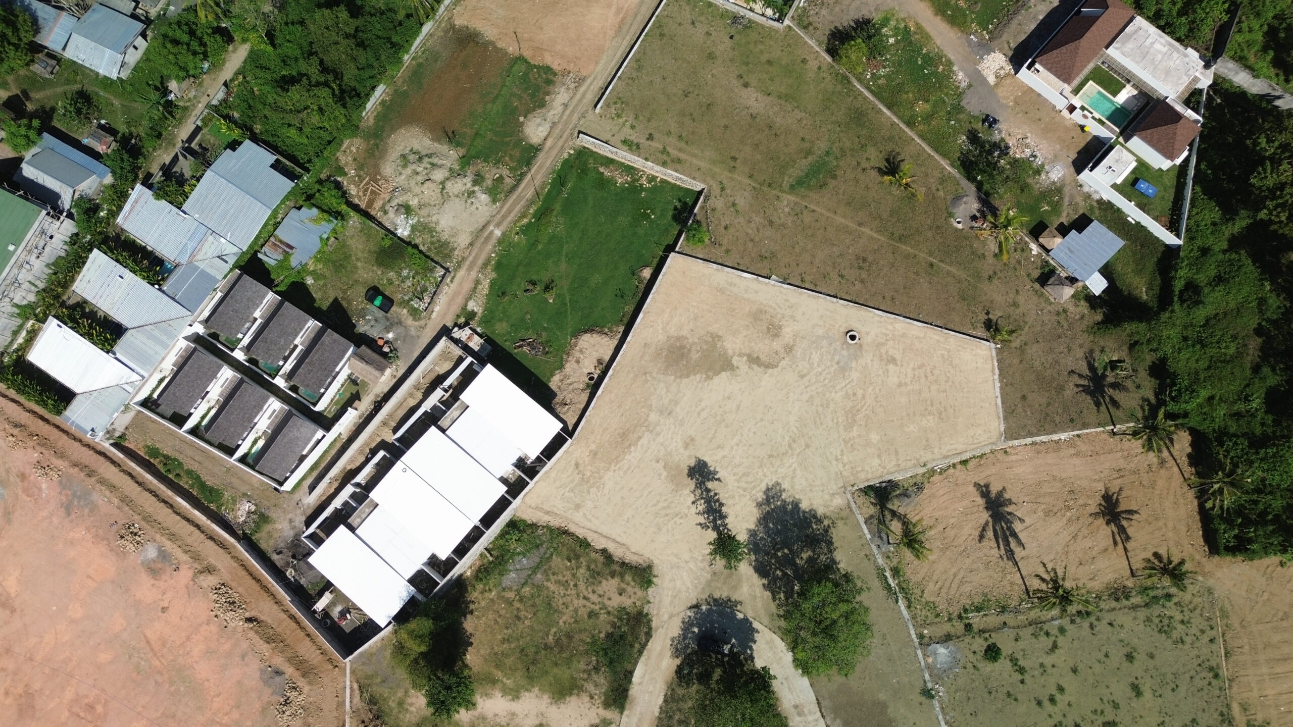 Directly overhead drone shot of the cleared plot situated next to existing residential structures.