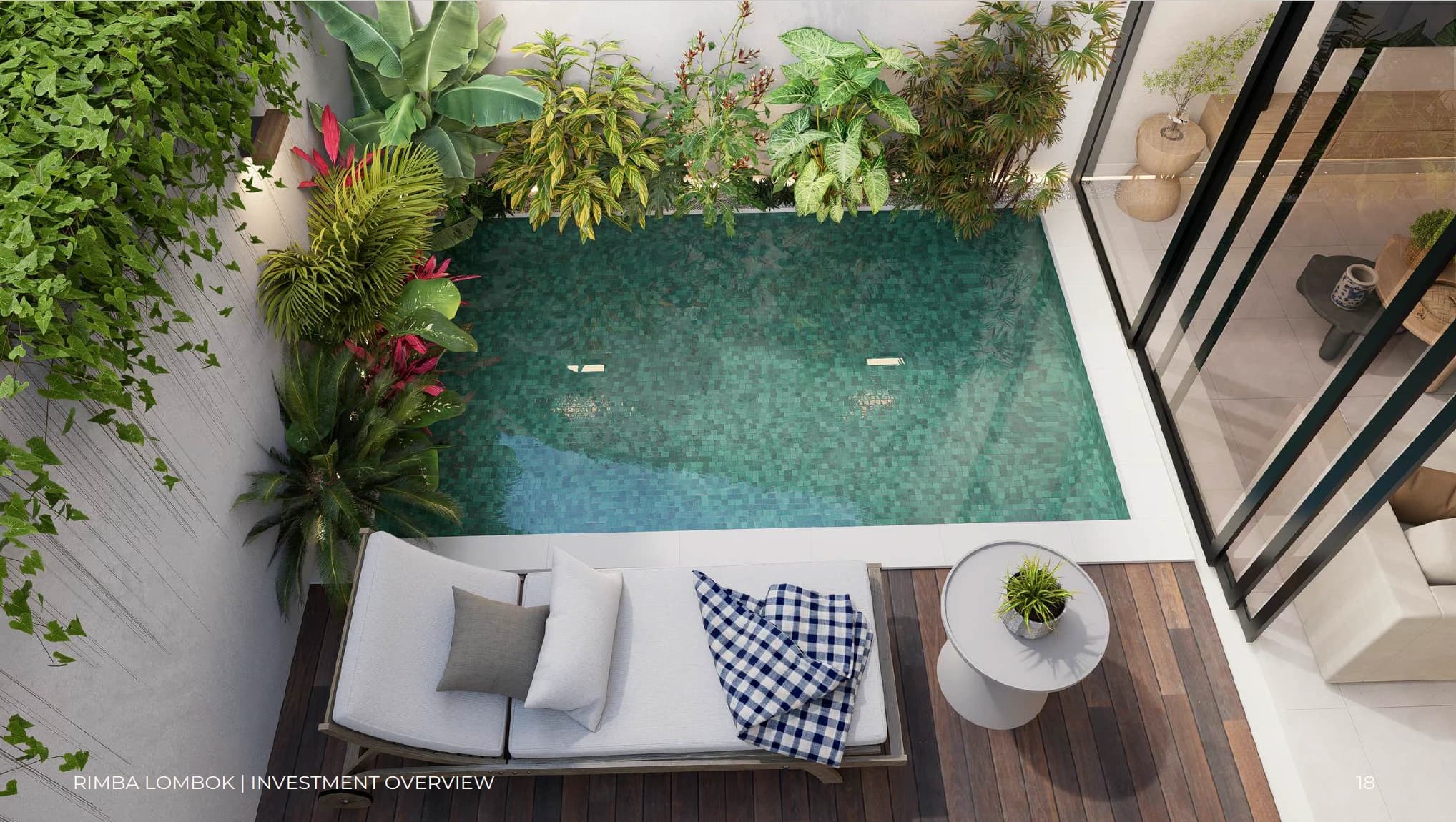 Top-down view of a private courtyard pool surrounded by tropical greenery and a wooden lounge deck with a sunbed.