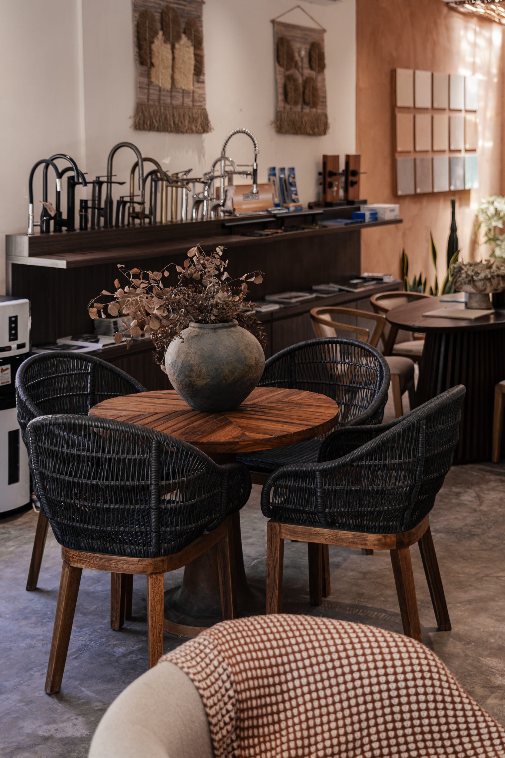 Seating area with woven chairs and a parquet table, backed by product displays.