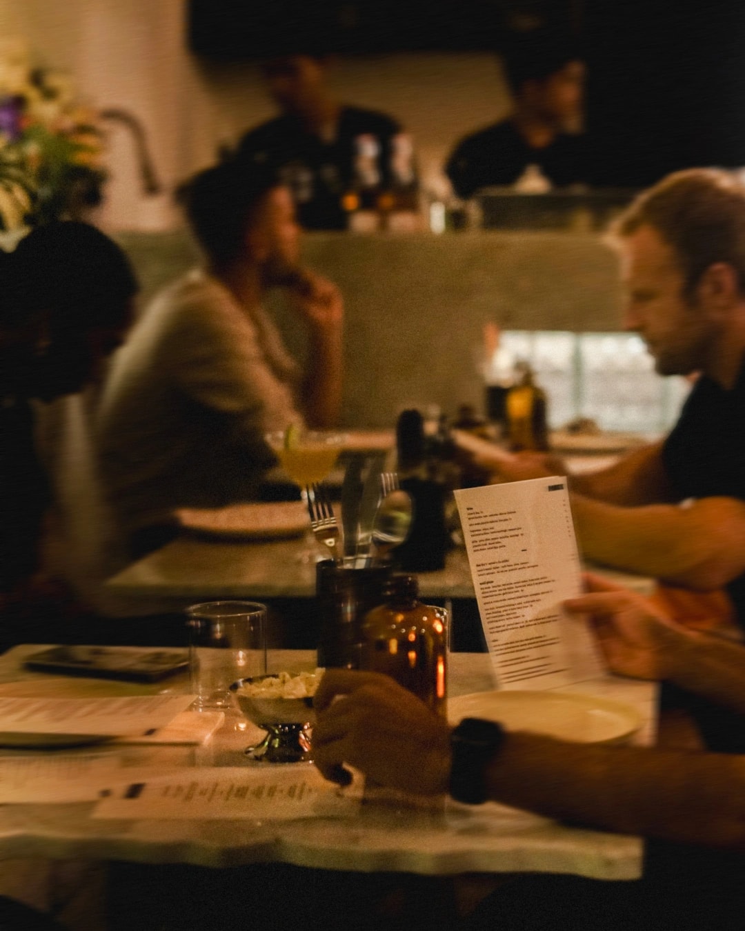 Warmly lit restaurant interior with diners seated at tables, enjoying a meal in a cozy and intimate atmosphere.