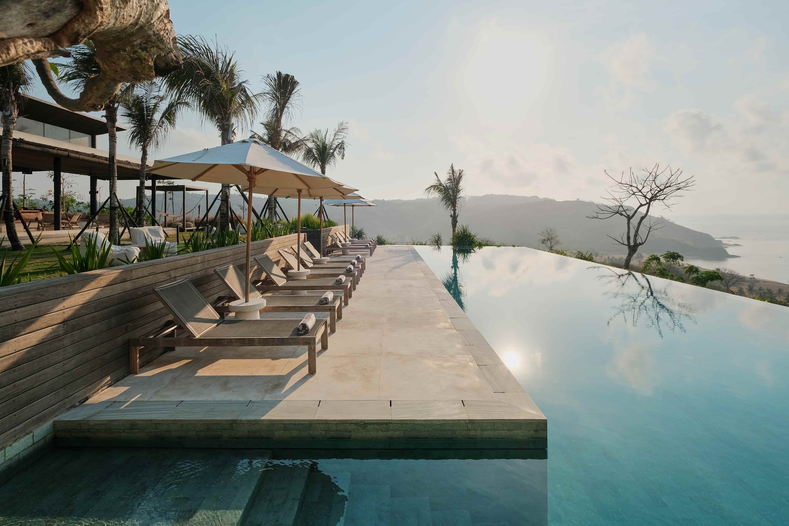 nfinity pool with lounge chairs and expansive ocean views.
