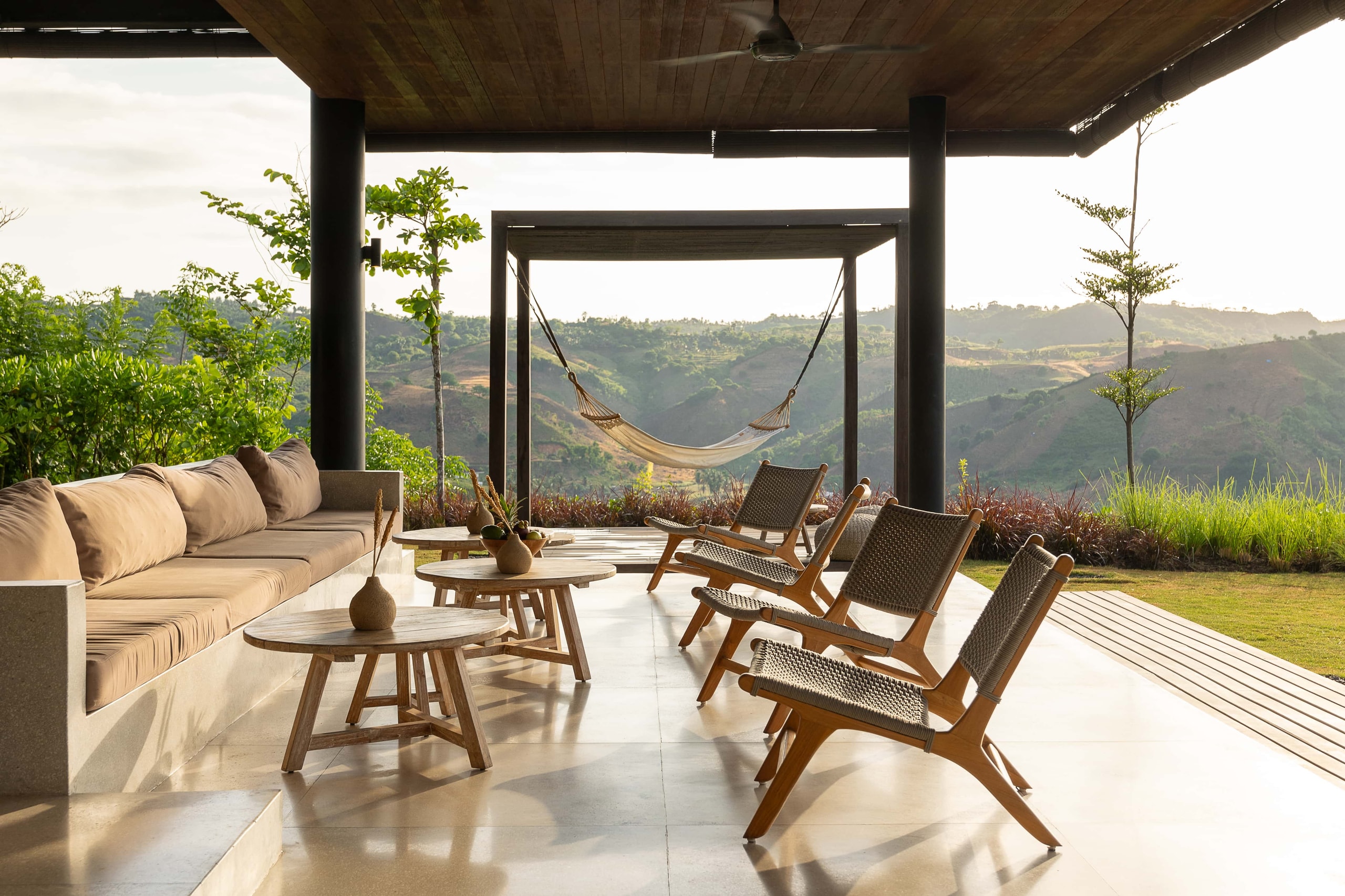 Covered outdoor lounge with a hammock and hillside vistas.