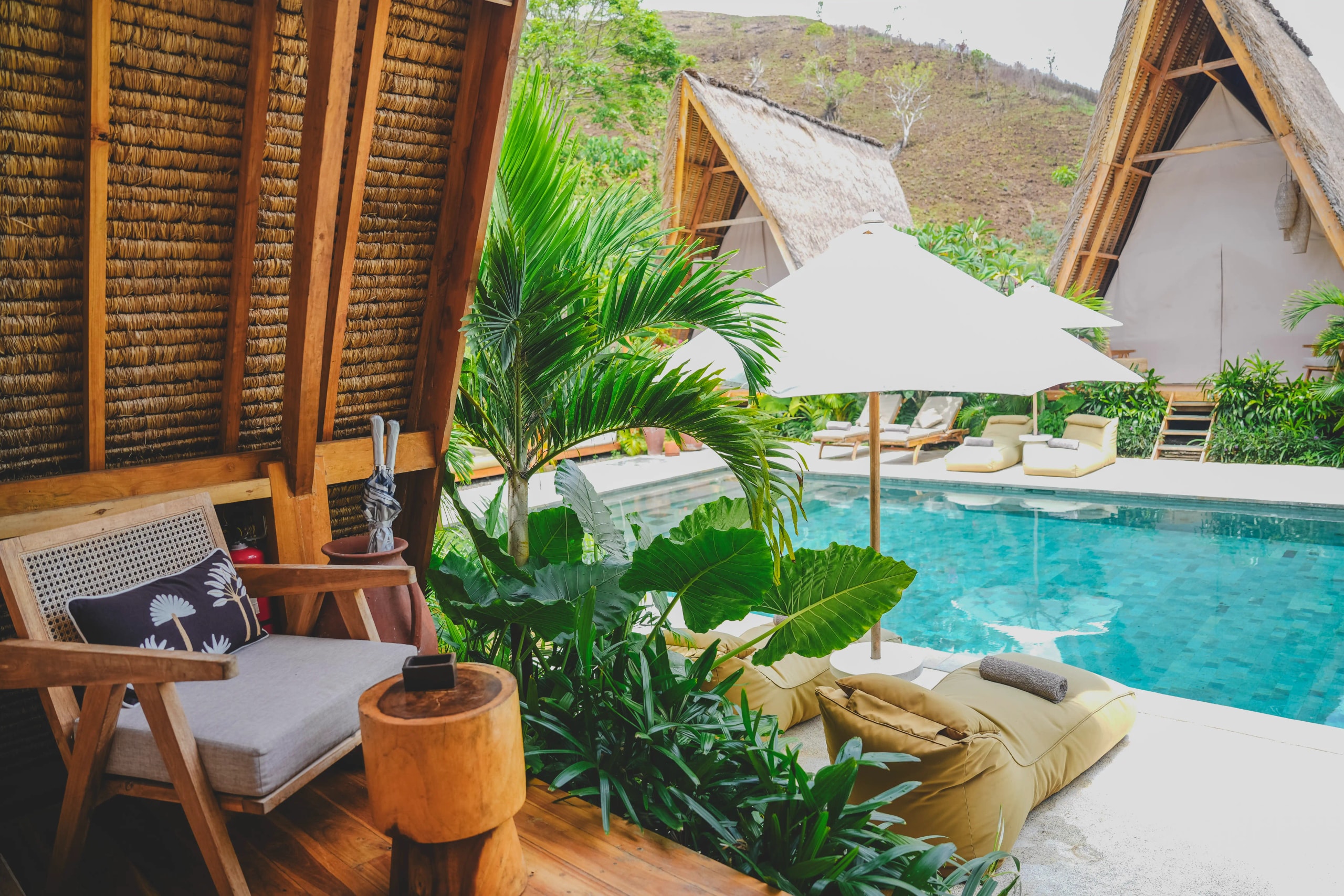View from a glamping tent terrace looking out onto bean bag loungers and a swimming pool.