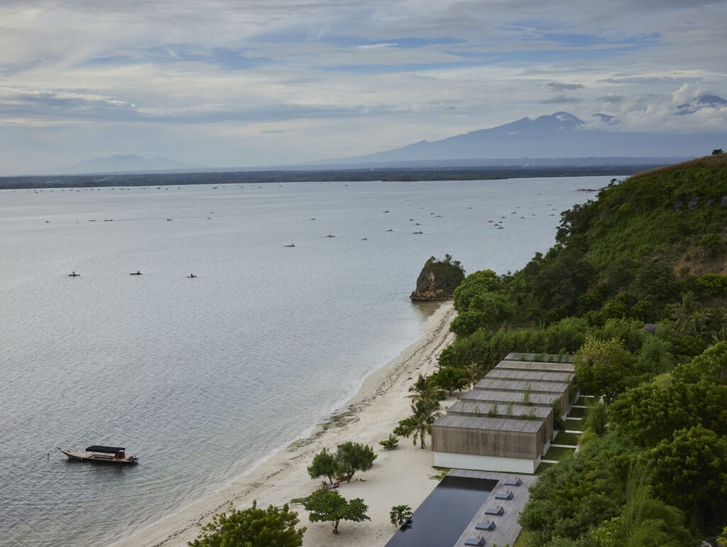 Aerial view of a beachfront resort tucked between lush hills and the ocean.