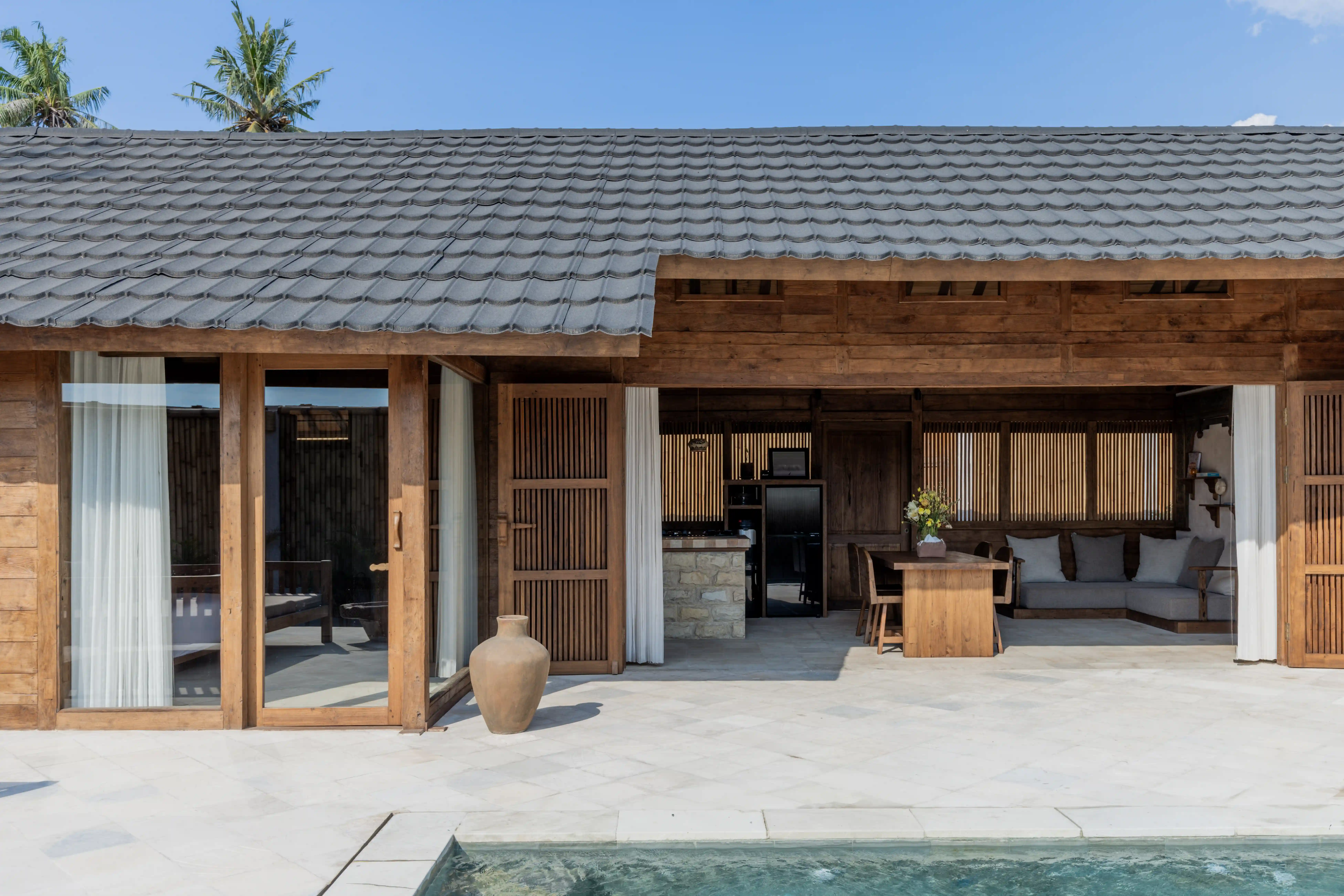 Open-concept wooden villa featuring a dining area, outdoor patio, and a private swimming pool.