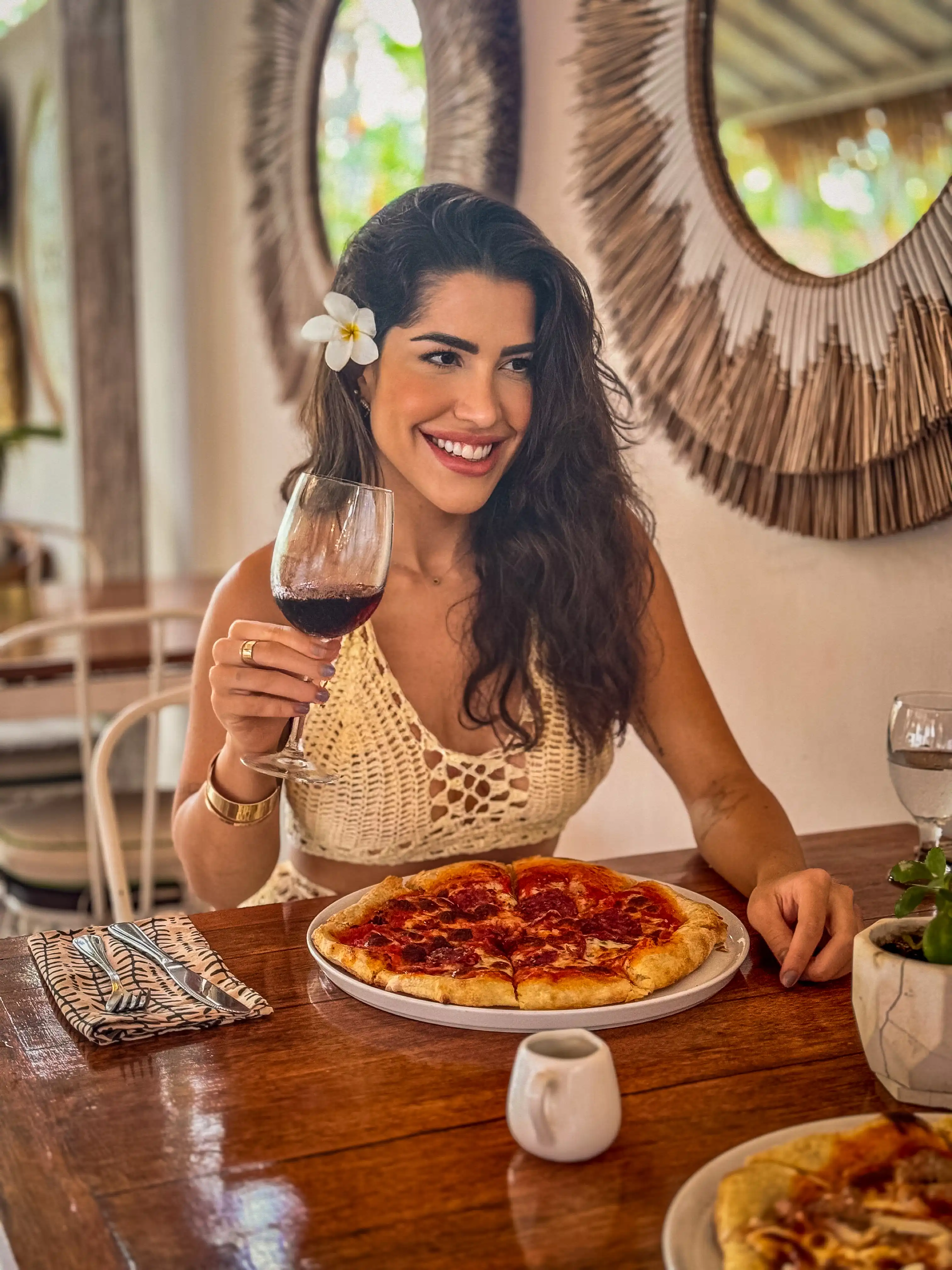 Woman enjoying pizza and red wine at L’Osteria dell’Isola restaurant.