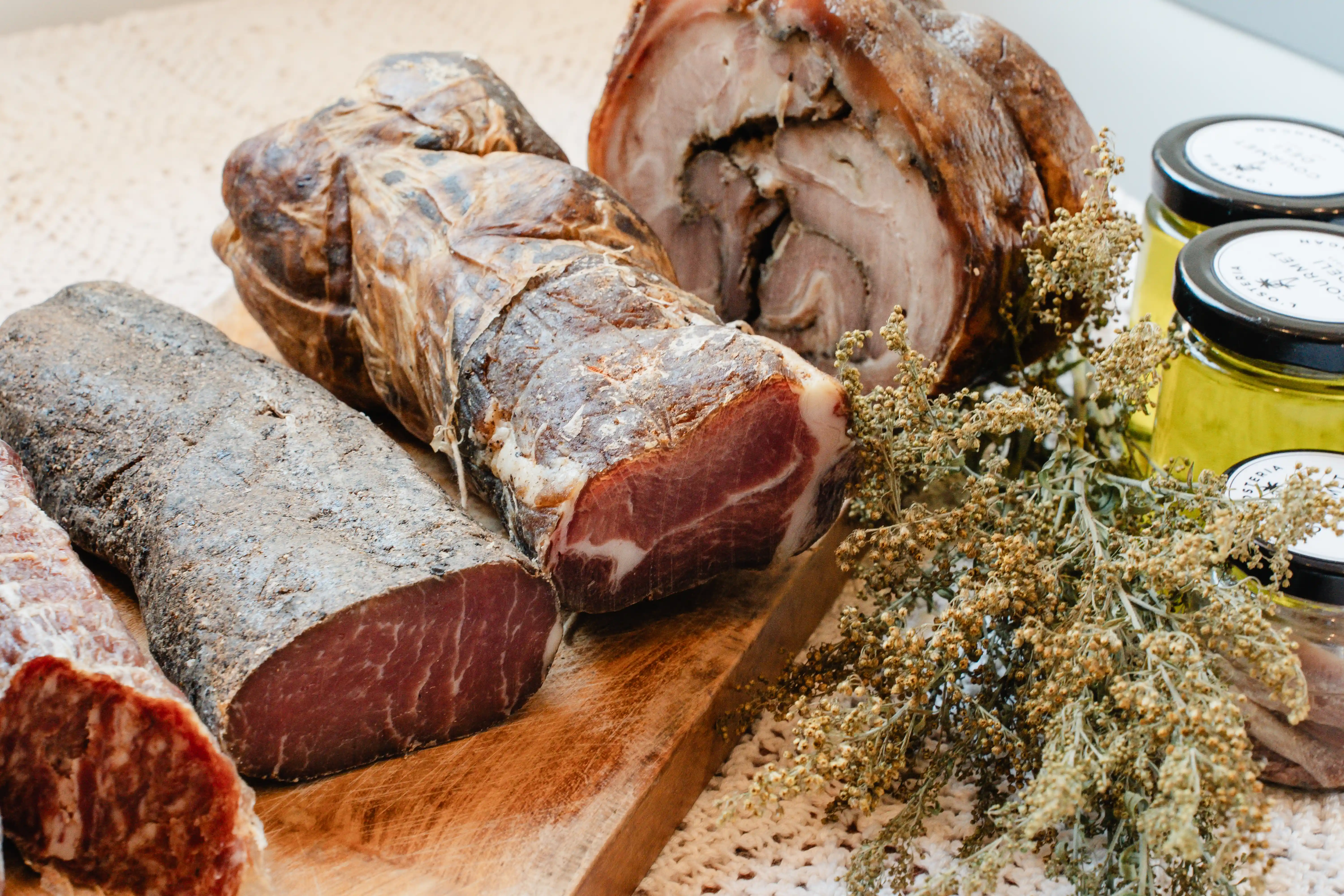 Selection of cured meats and charcuterie with jars of condiments.