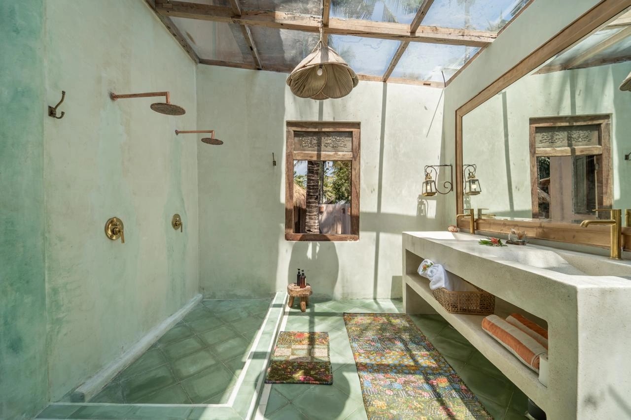 Salle de douche lumineuse sous toit vitré avec double pommeau et grand miroir.