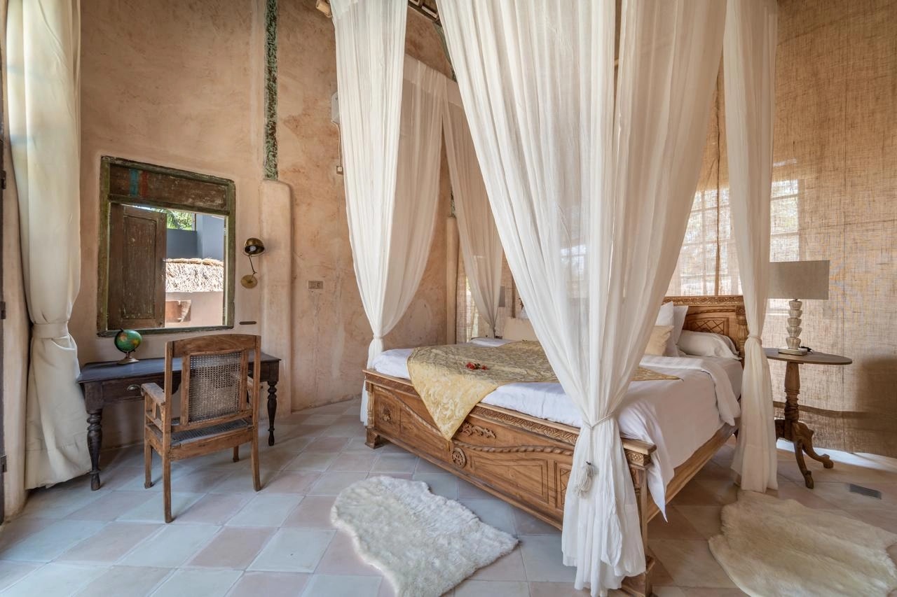 Chambre spacieuse au style tropical avec lit à baldaquin et bureau en bois.