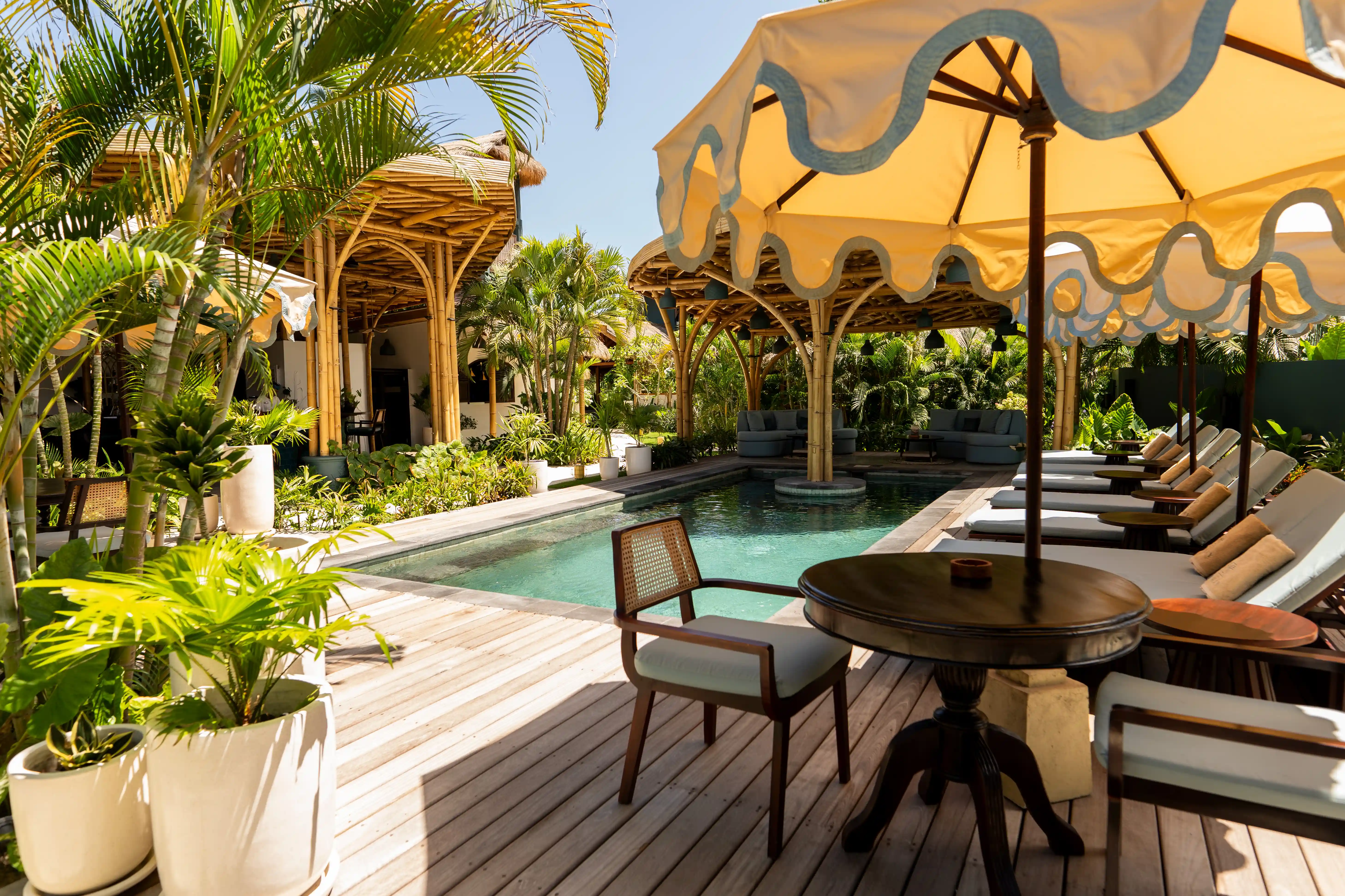 Outdoor resort lounge and pool area framed by bamboo structures and tropical greenery.