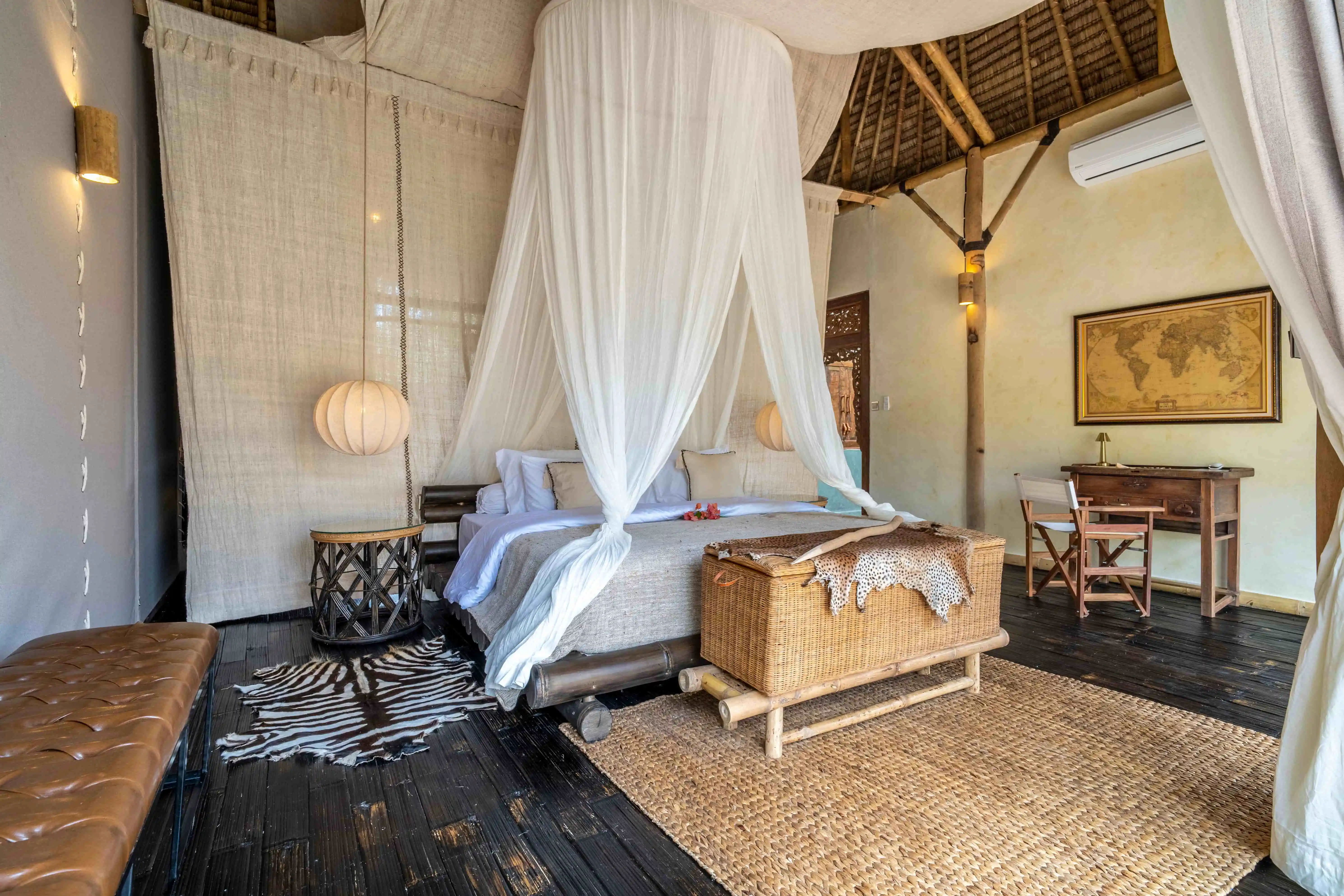 Luxury master bedroom with a king-size canopy bed, handcrafted wooden furniture, and elegant tropical interiors.