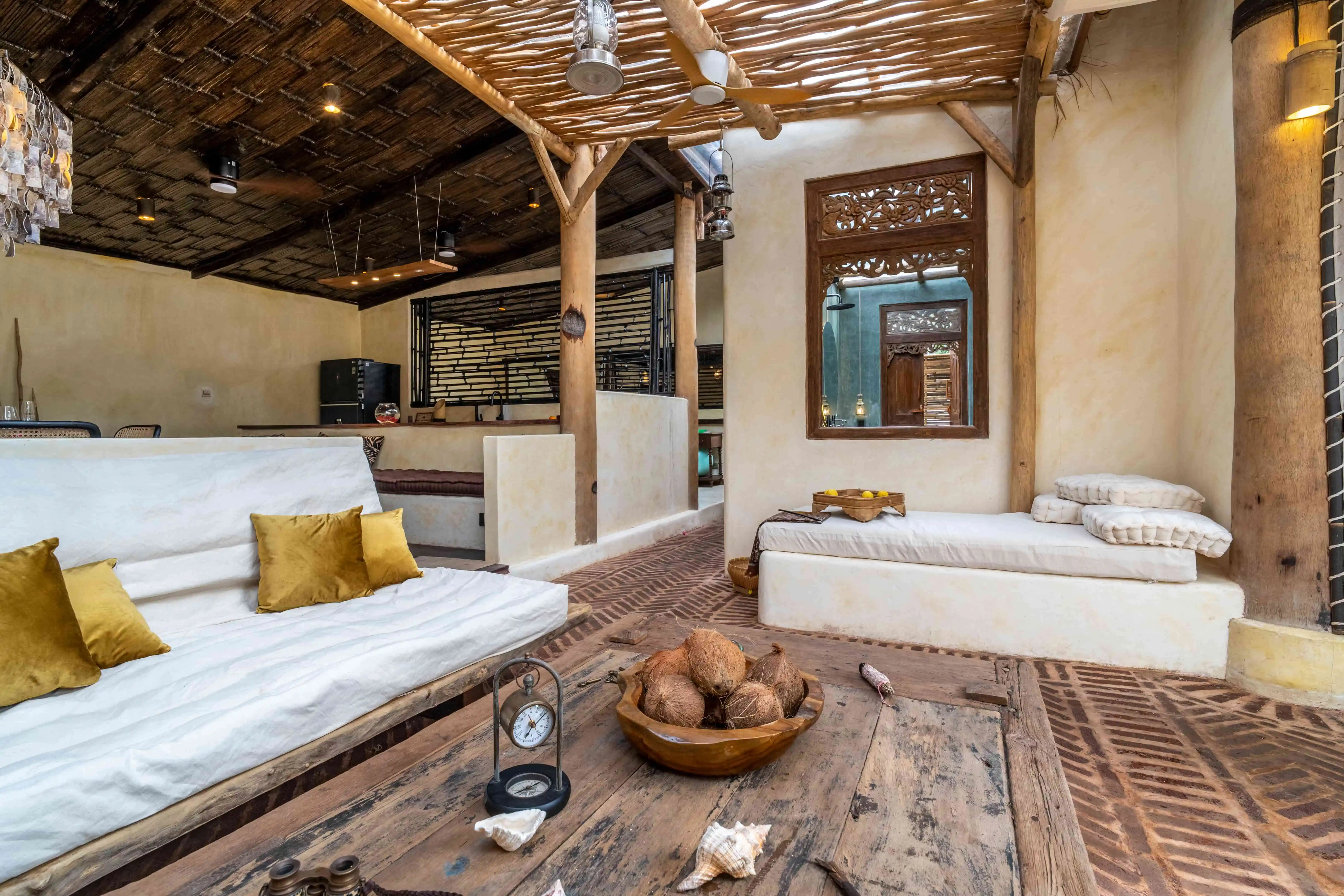 Open-plan tropical villa living room with rustic wooden furniture, lounge seating, and handcrafted natural décor.