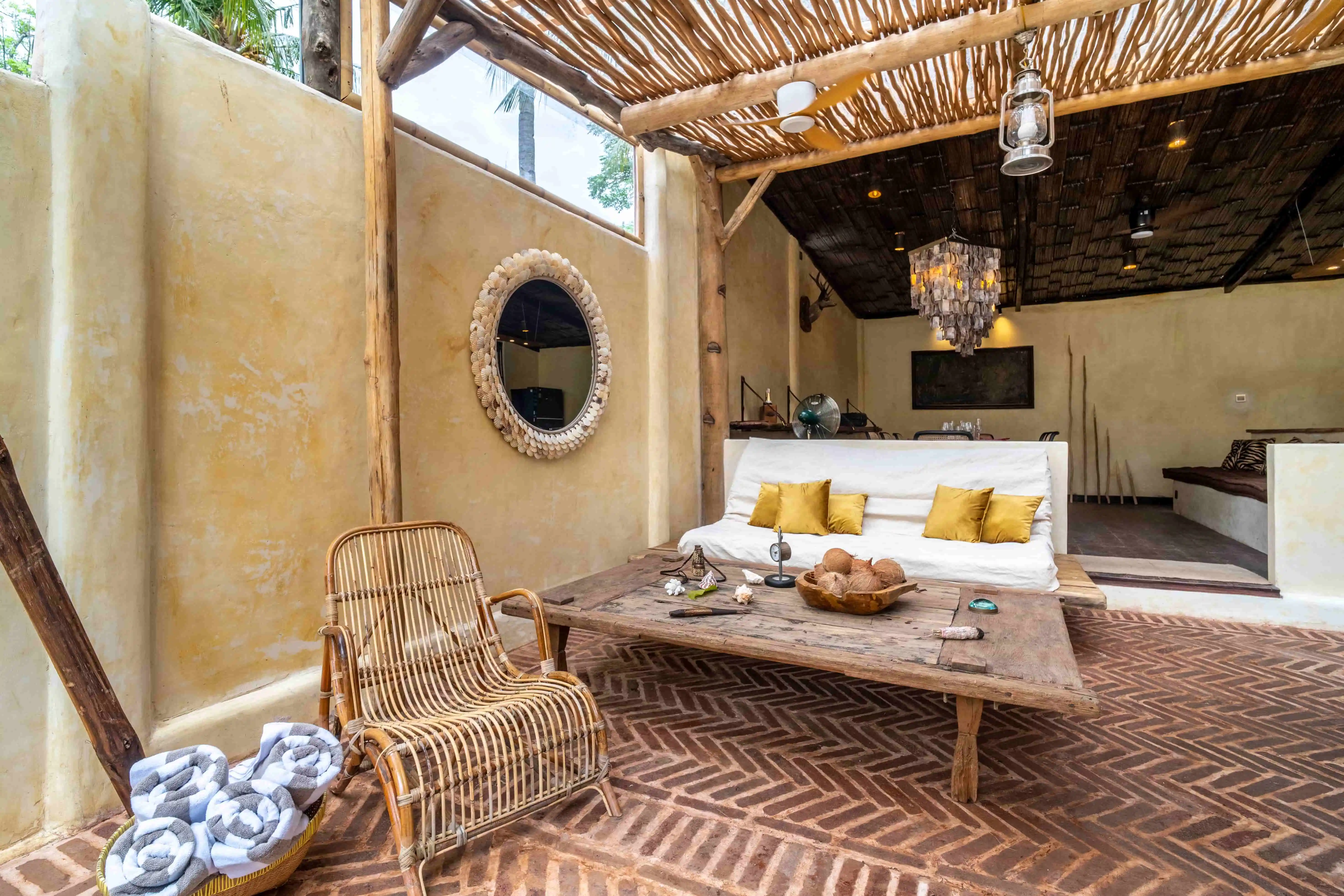 Covered outdoor lounge with comfortable daybeds, rustic wooden furniture, and seamless indoor-outdoor tropical living.