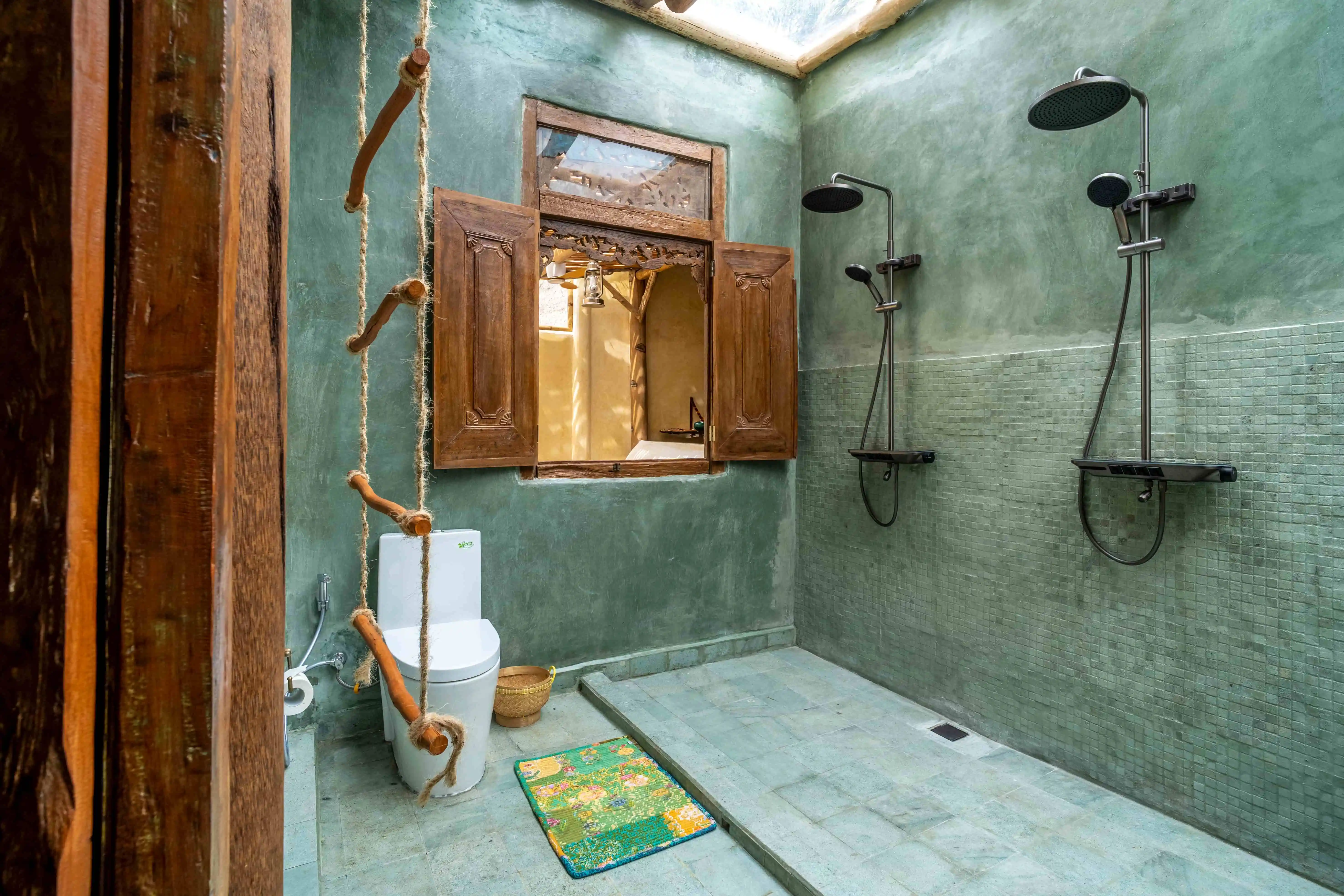 Spacious open-air bathroom with dual rainfall showers, natural stone finishes, and tropical-inspired design.