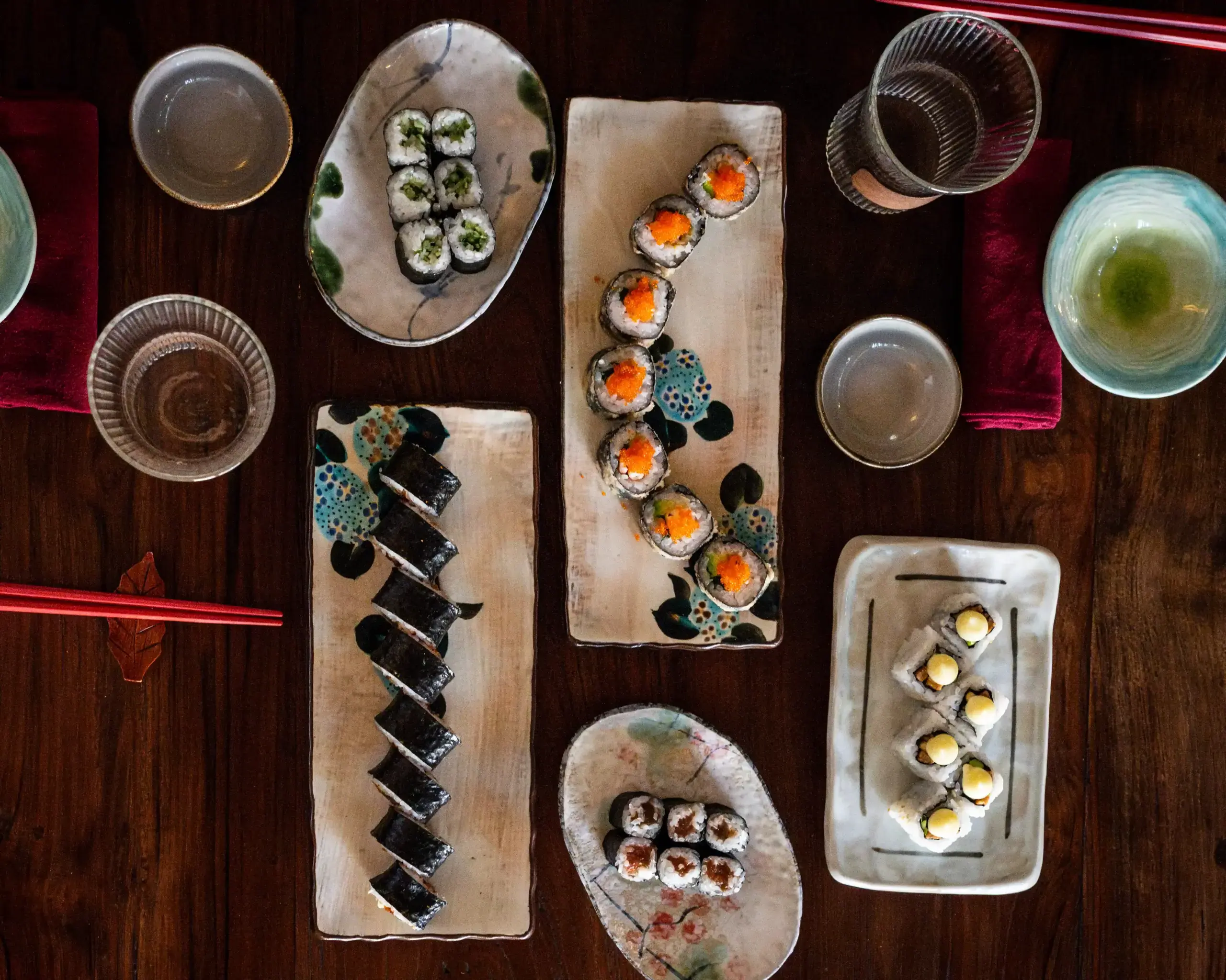 Top-down view of various sushi rolls and maki served on ceramic plates.
