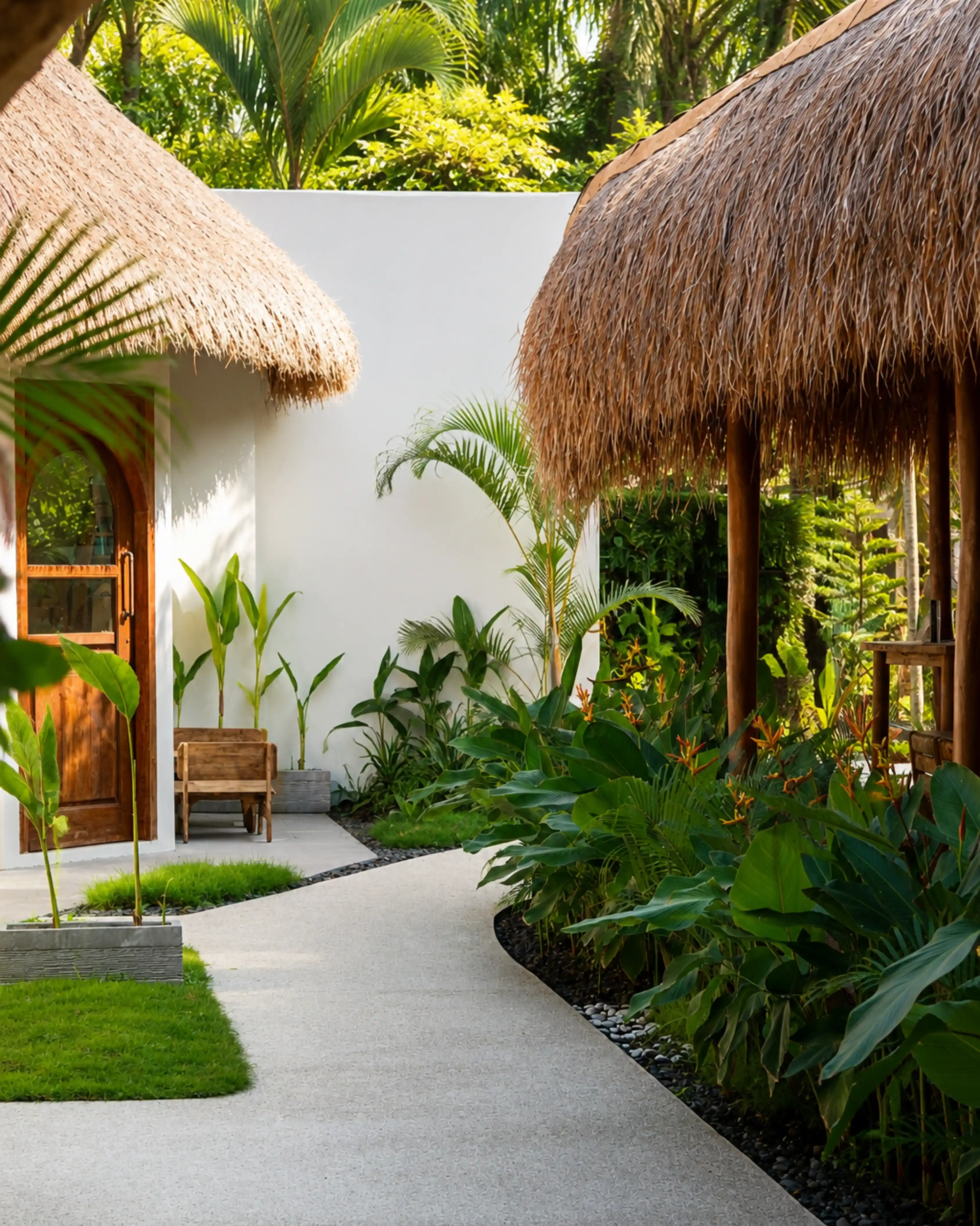 Tropical pathway with thatched-roof huts and lush green foliage.