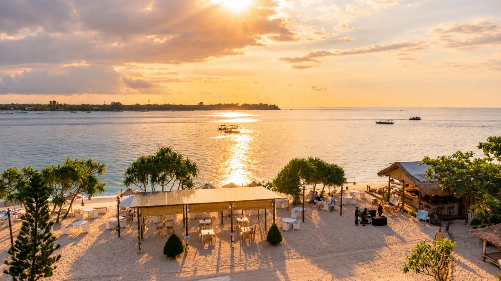 Sunset view over a beachfront dining area and calm tropical sea.
