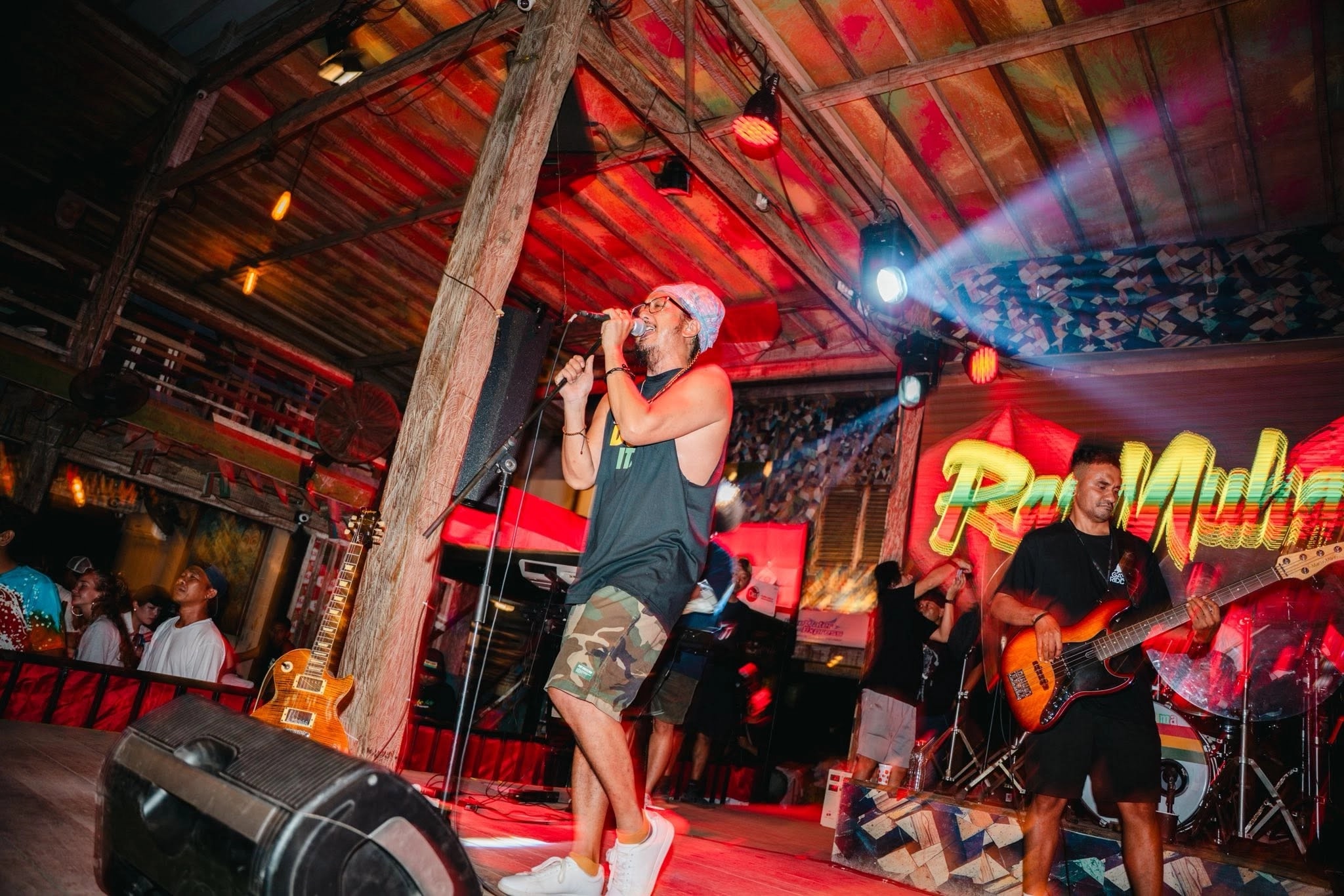 Male singer performing on stage under red lights with a live band.