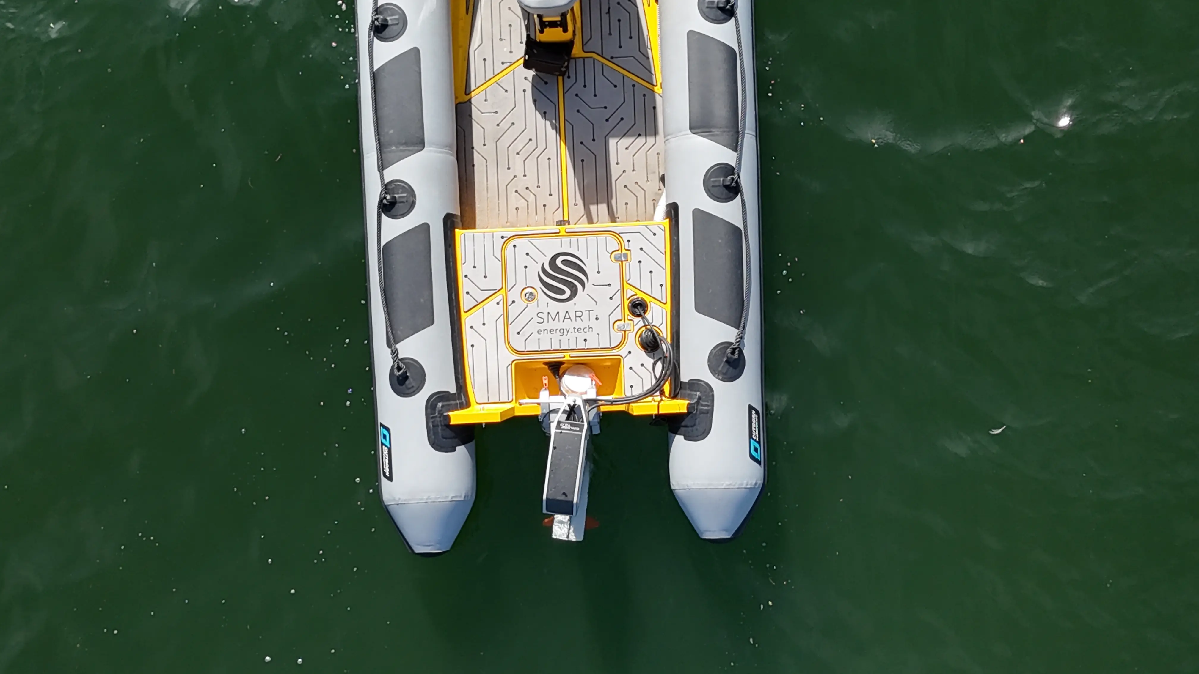 Top-down view of an electric inflatable boat on dark green water branded with "SMART energy.tech"