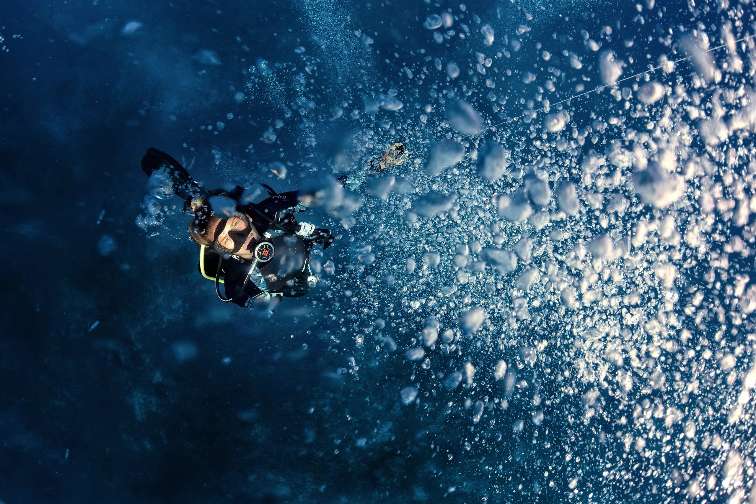: Diver underwater looking up through a cloud of air bubbles