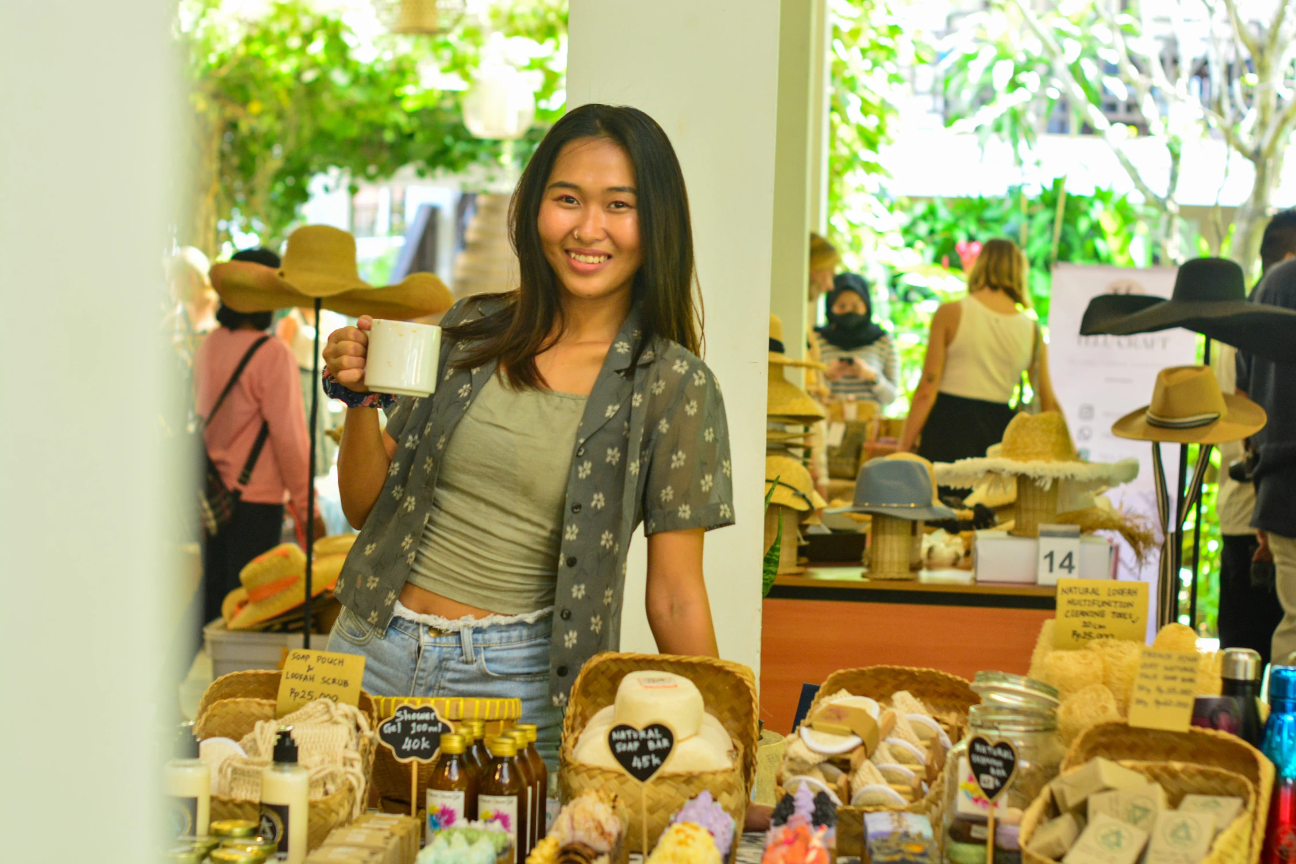 Woman holding a mug and smiling behind a market display table