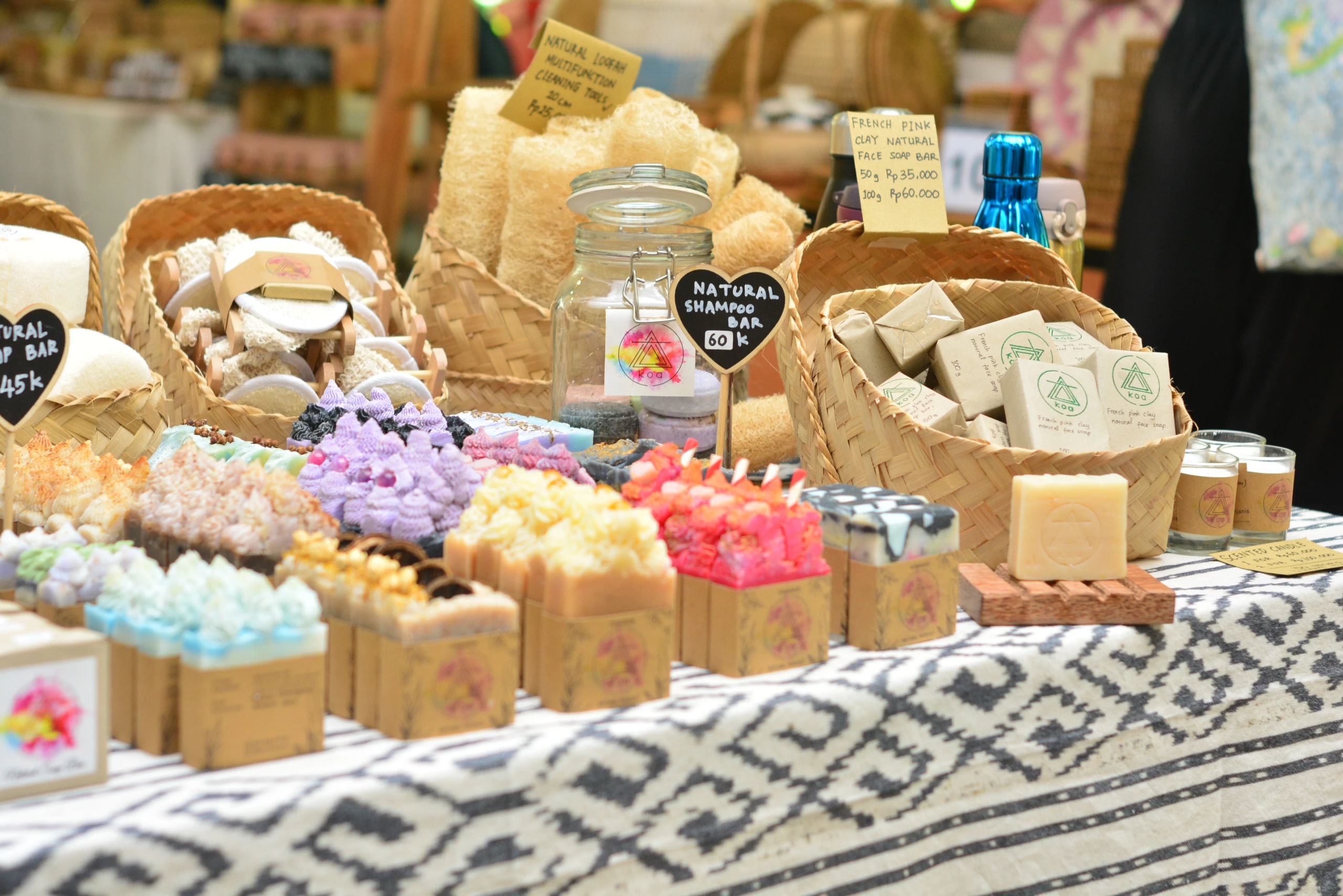 Handmade natural soap bars and loofahs displayed on a patterned tablecloth