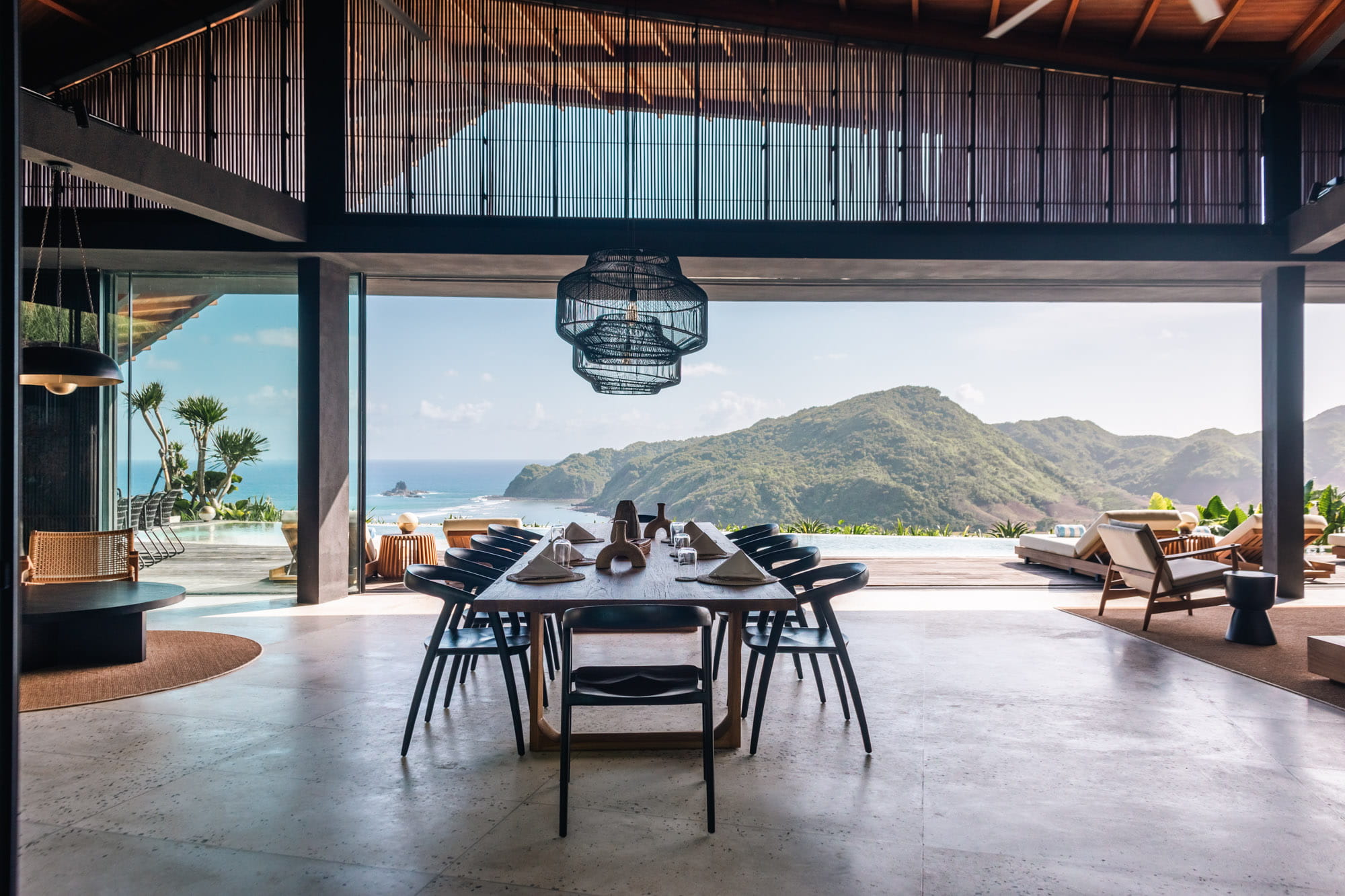 The ultra-luxury interior of Villa Layang, South Lombok, featuring a chic modern living room with large glass doors opening to a private balcony and ocean views.
