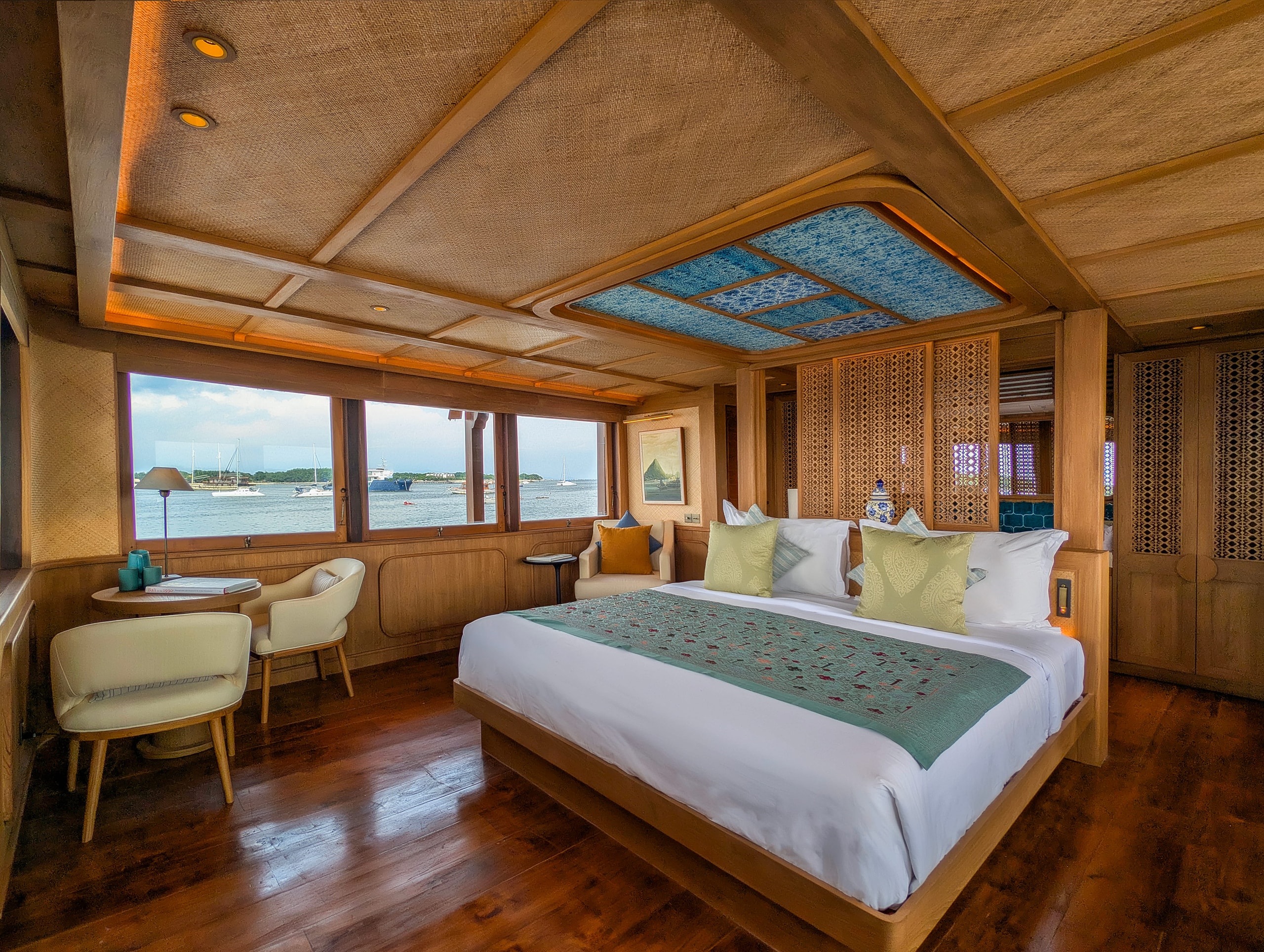 Luxury cabin interior of Jeeva Samudera Phinisi yacht featuring a king-size bed with traditional wooden accents and ocean views.