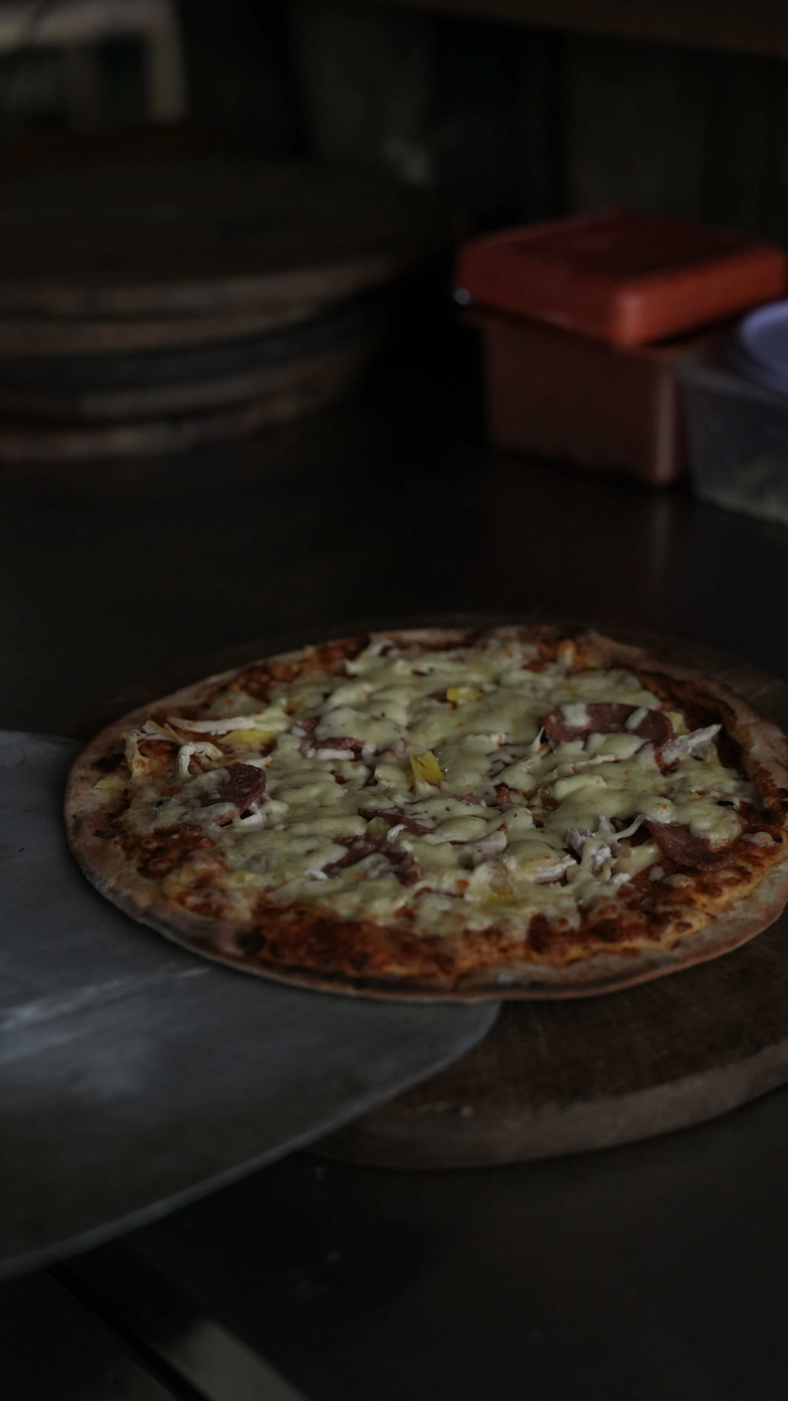 A freshly baked thin-crust pizza topped with melted cheese and pepperoni, resting on a wooden board.