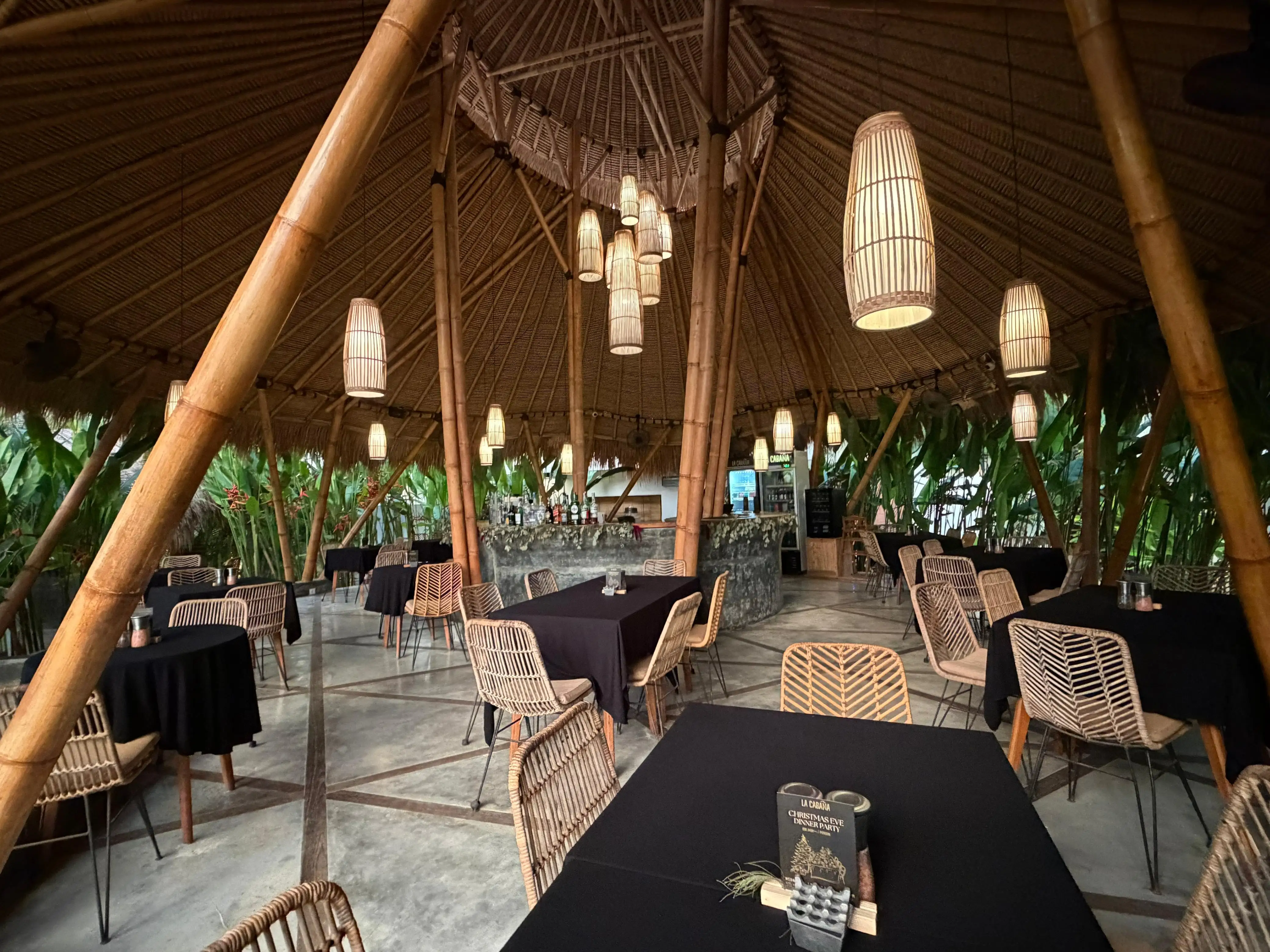 Bamboo dome restaurant interior with wicker pendant lights and black-clothed dining tables.
