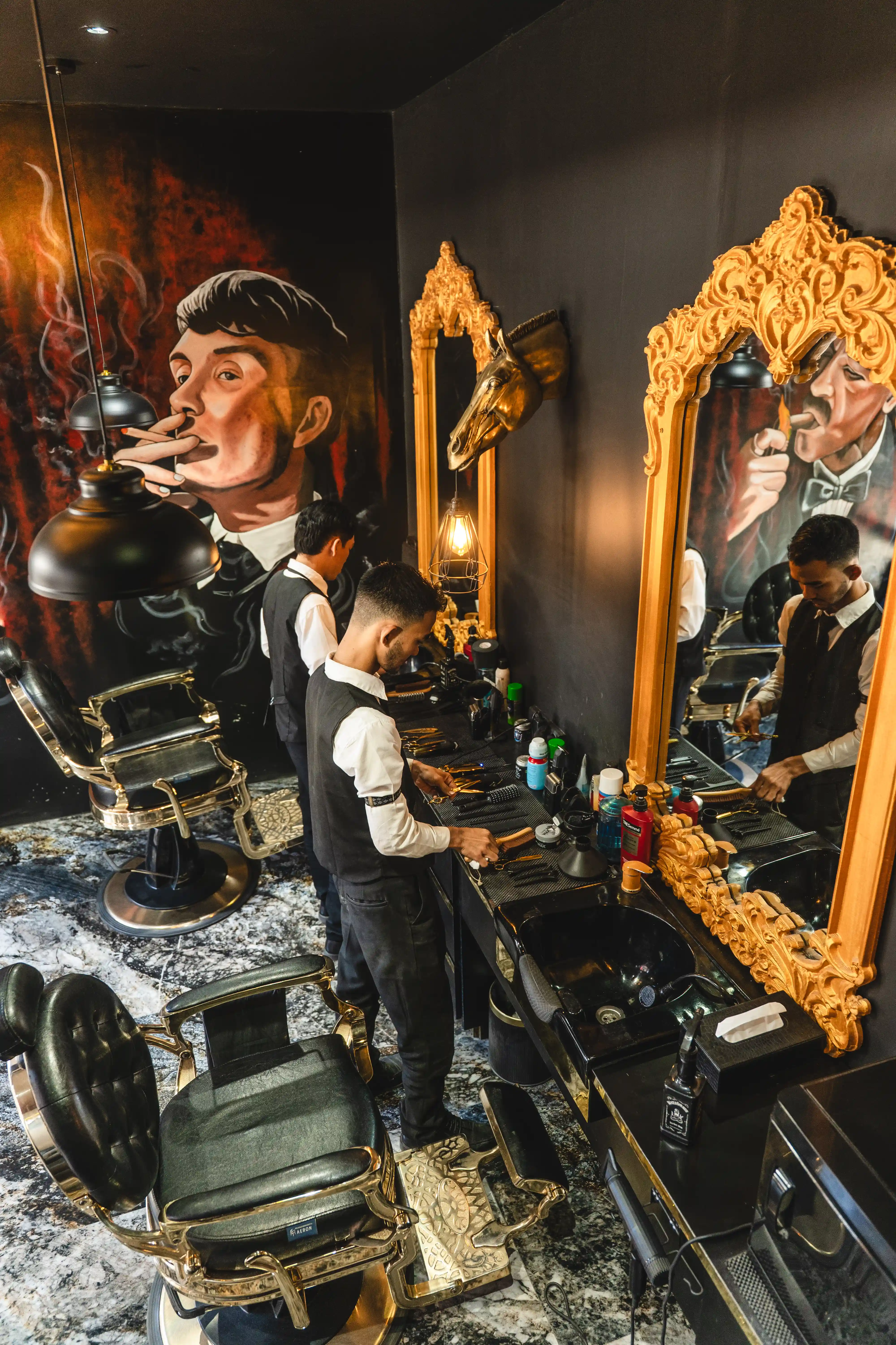 Interior of an ornate barbershop featuring gold-framed mirrors and vintage barber chairs.
