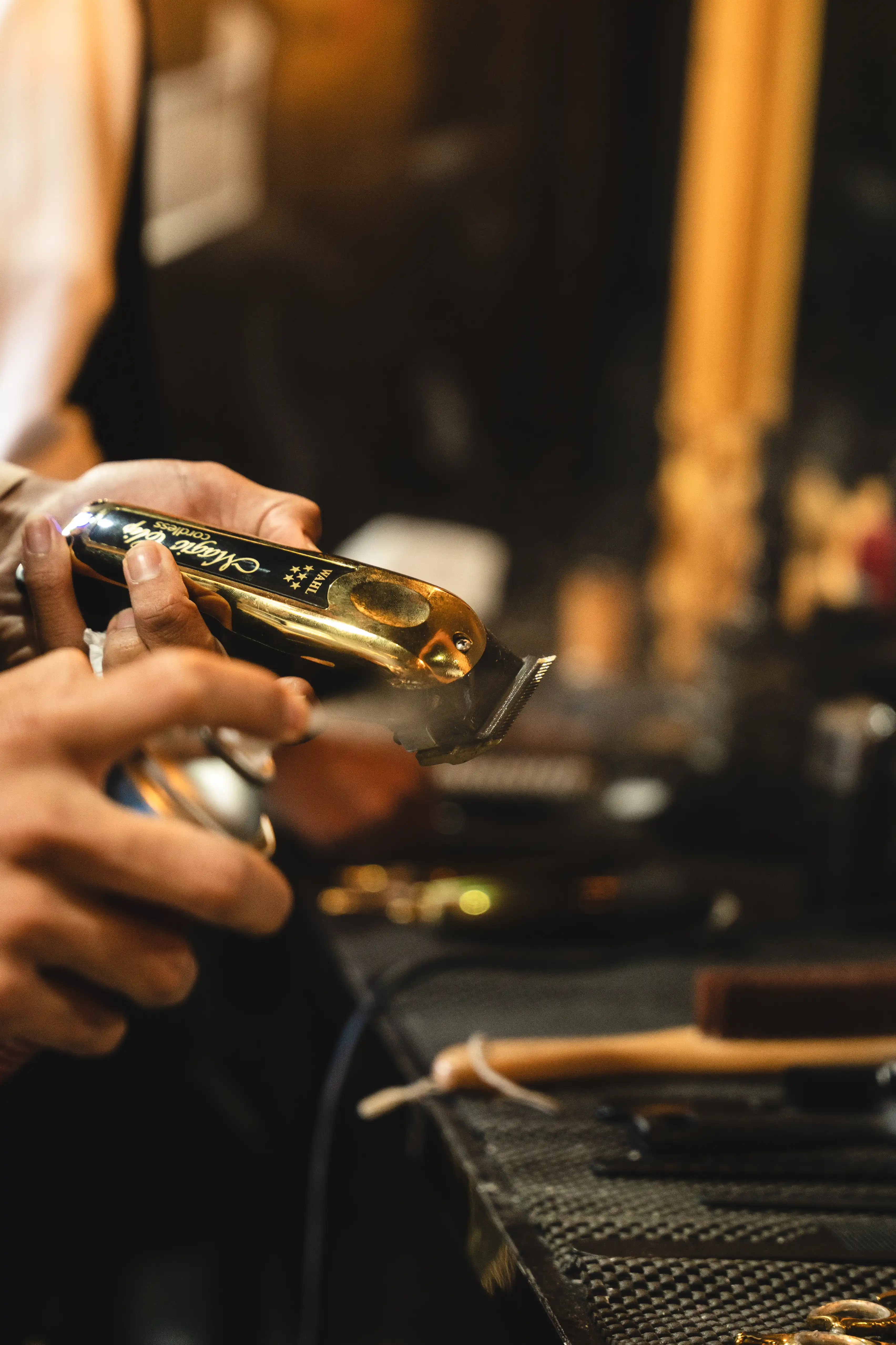 arber spraying cleaning spray onto a gold Wahl hair clipper.
