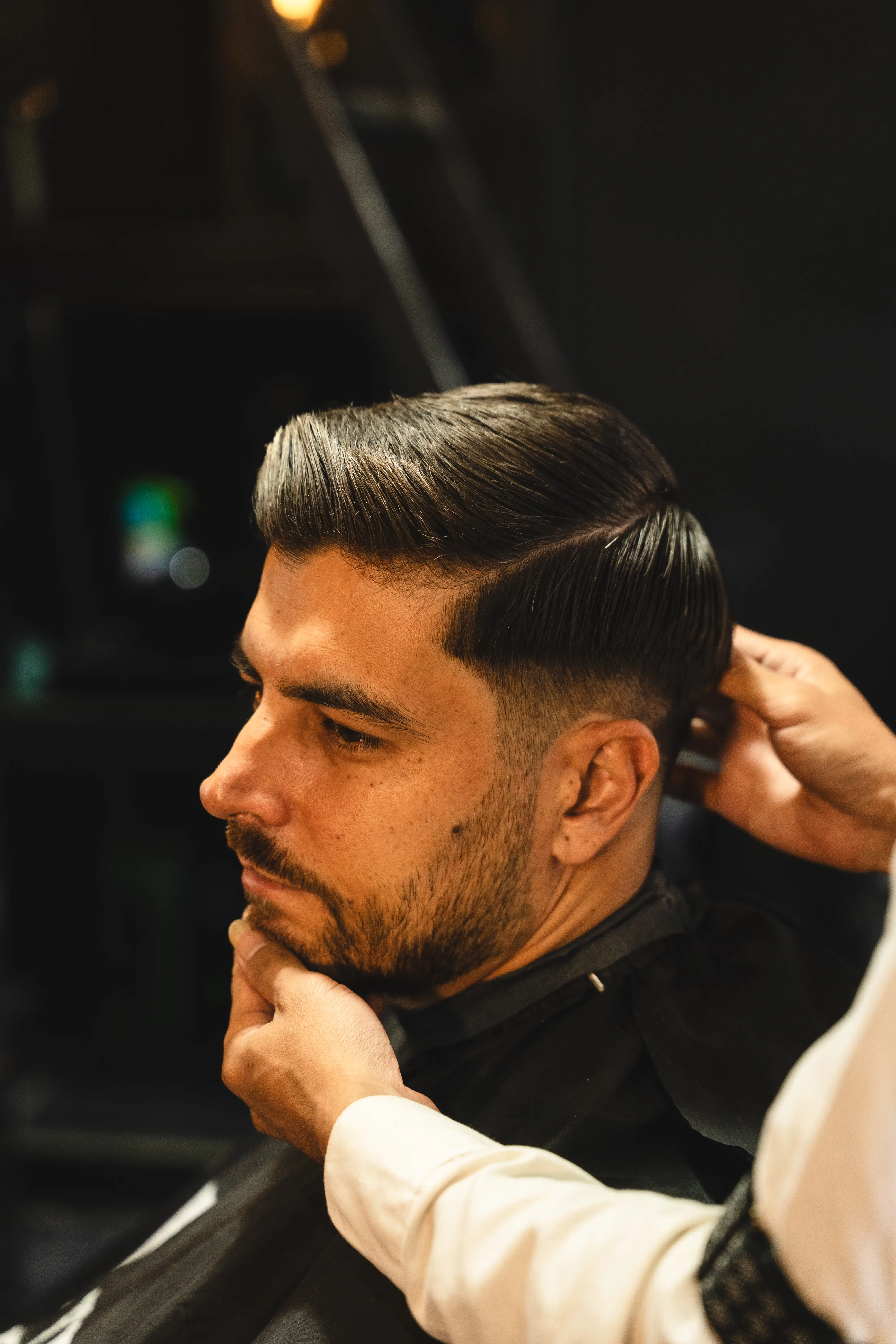 Close-up profile of a man with a fresh fade haircut and styled hair.
