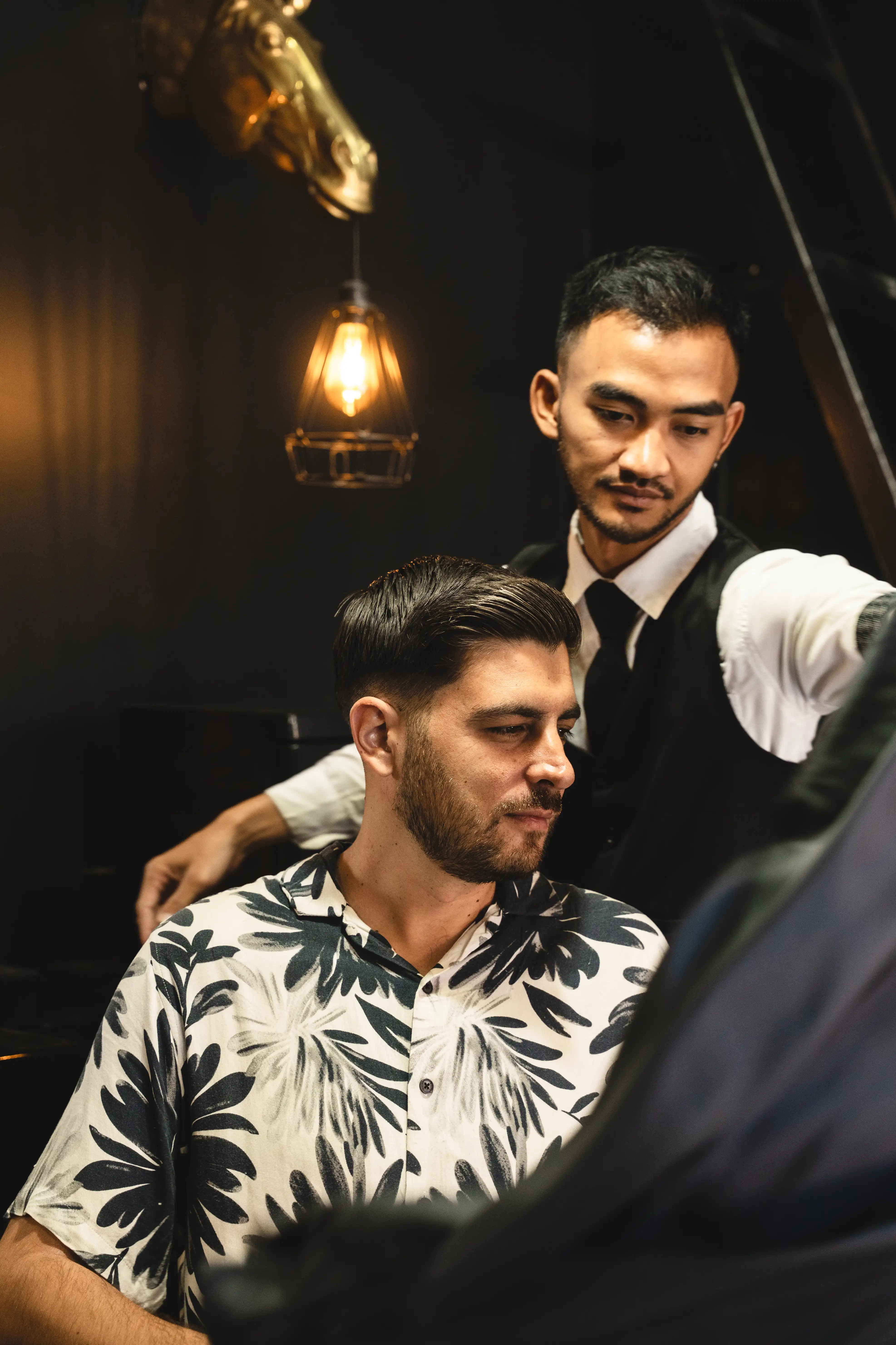 Barber placing a cape on a client seated in a barbershop chair.