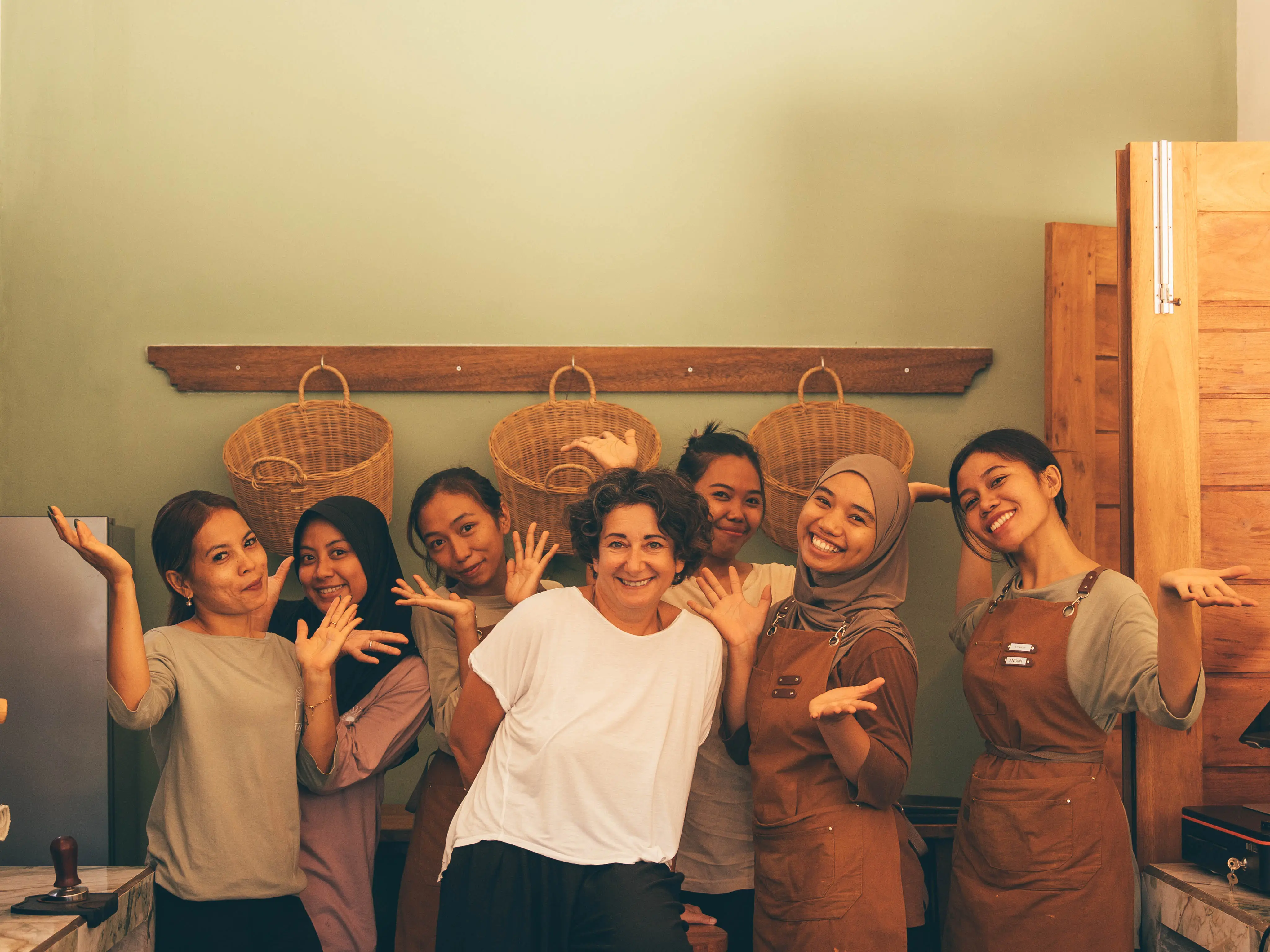 Group of staff members posing cheerfully together in a cafe.