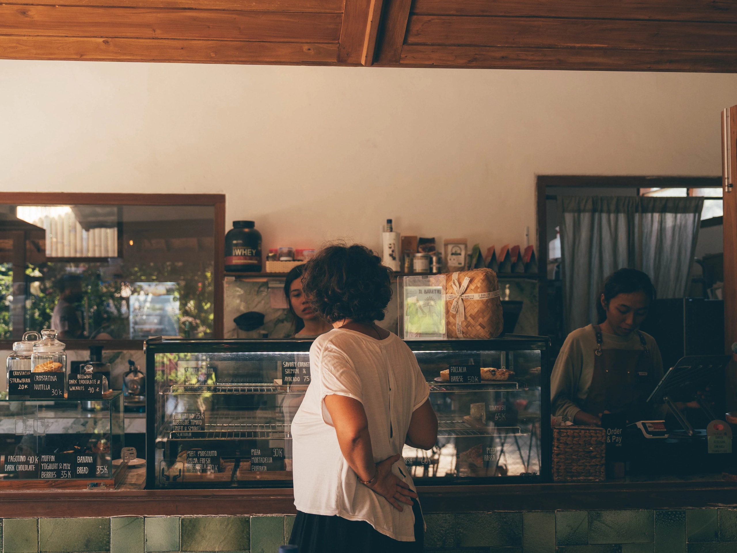 A Woman standing at the counter in a cafe.