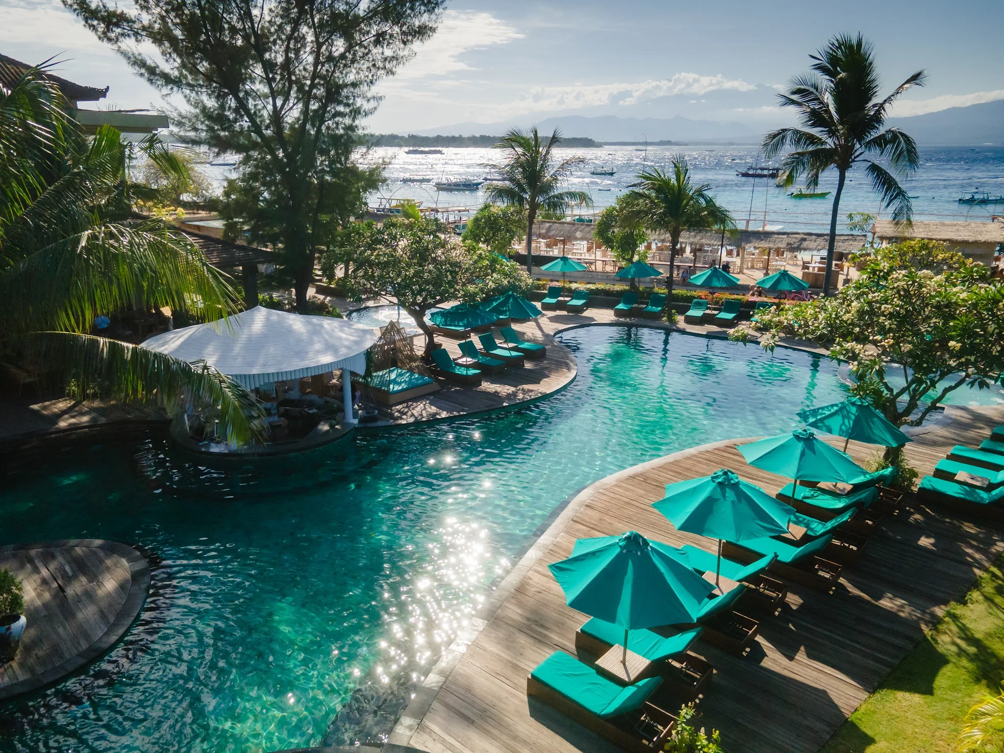 ropical pool deck with lounge chairs near the ocean.