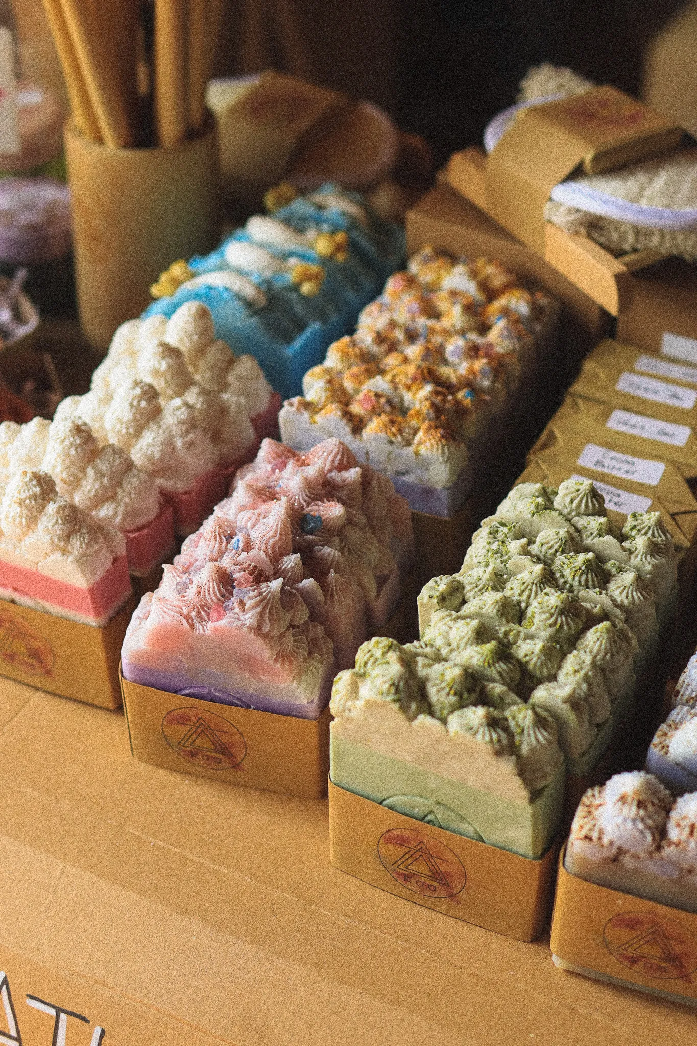 People browsing a market stall with handmade soaps and skincare products.